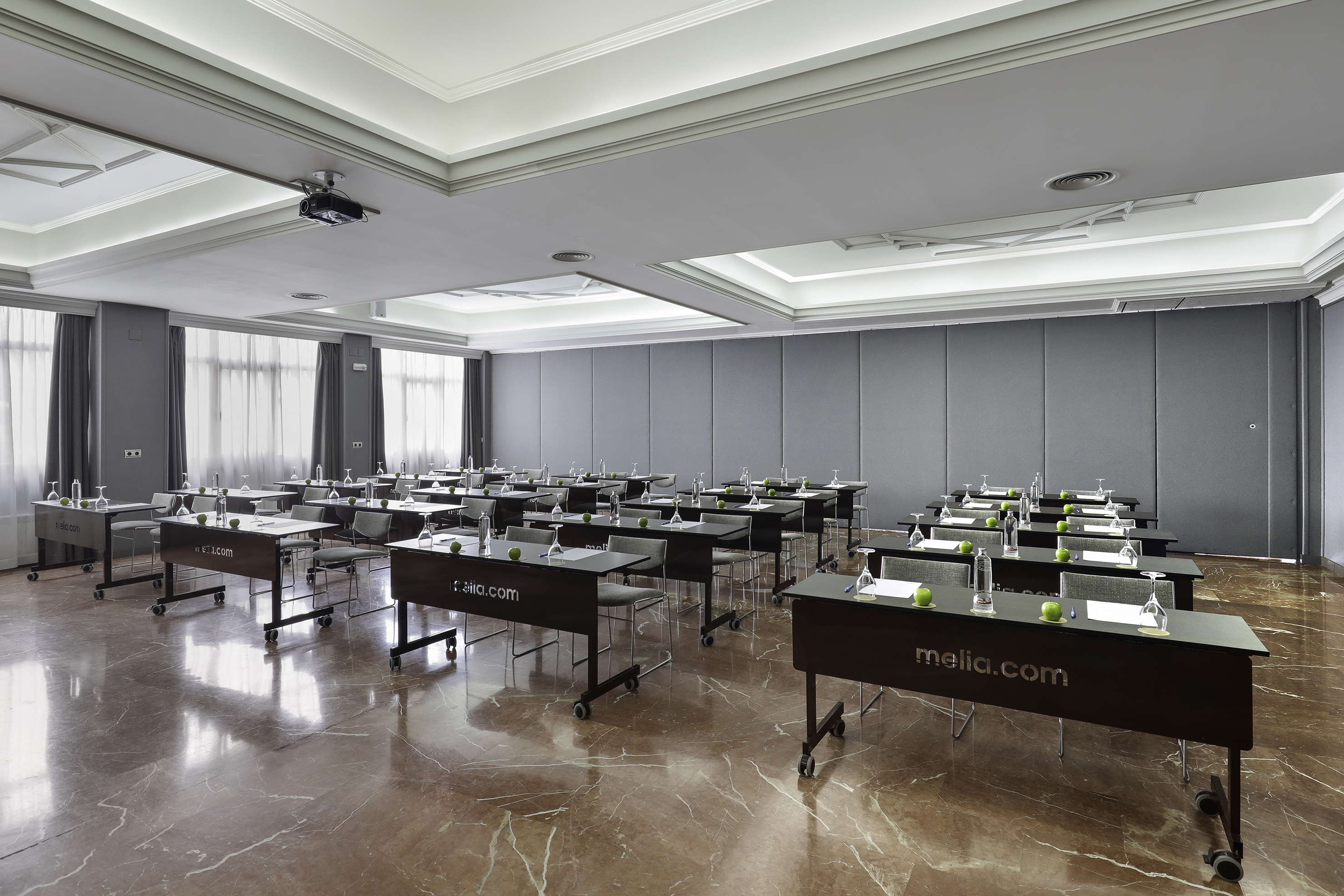 Melia hotel conference room, classroom style, with projector, tables, and apples.