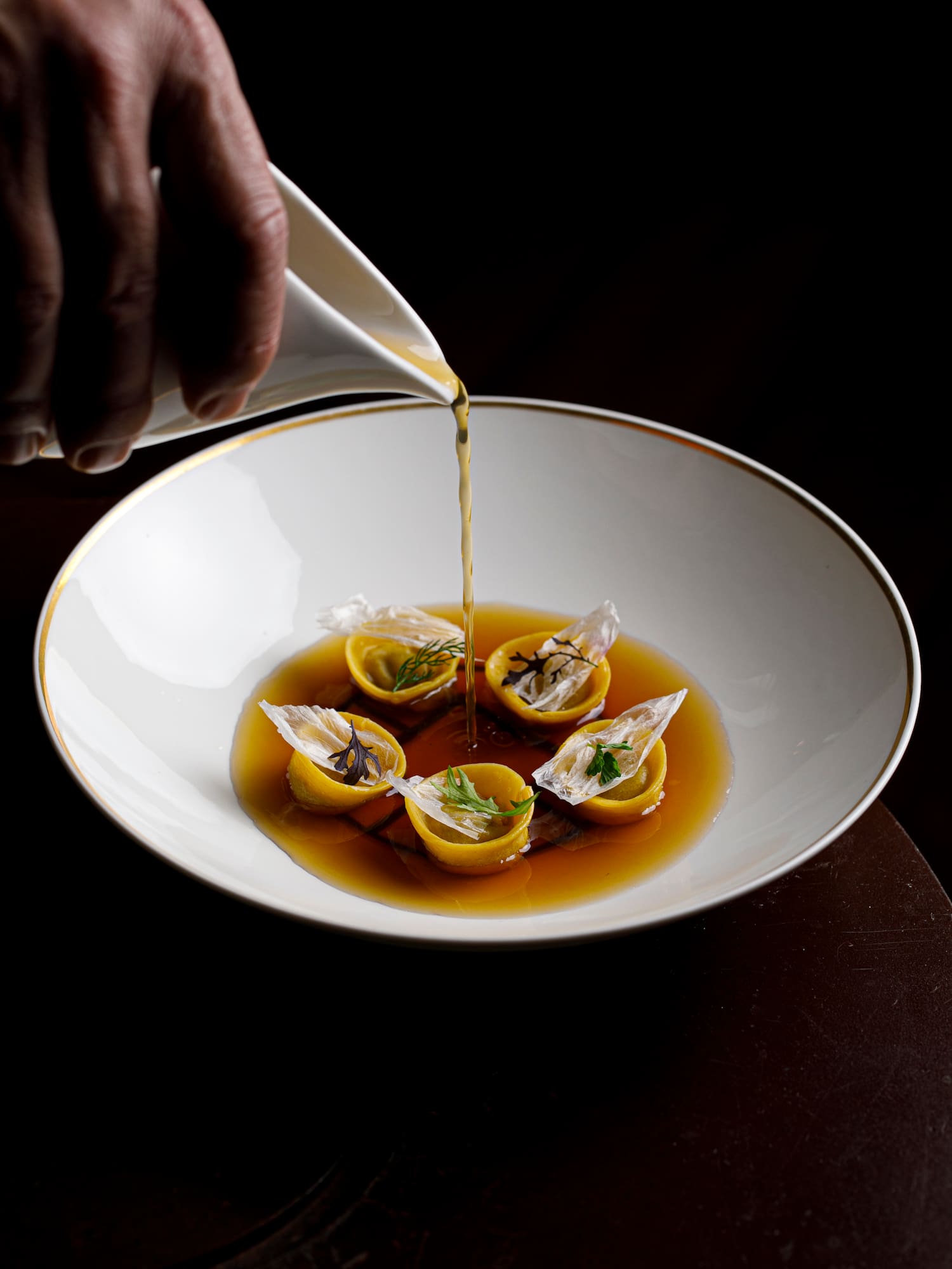 a person pouring liquid into a bowl of food