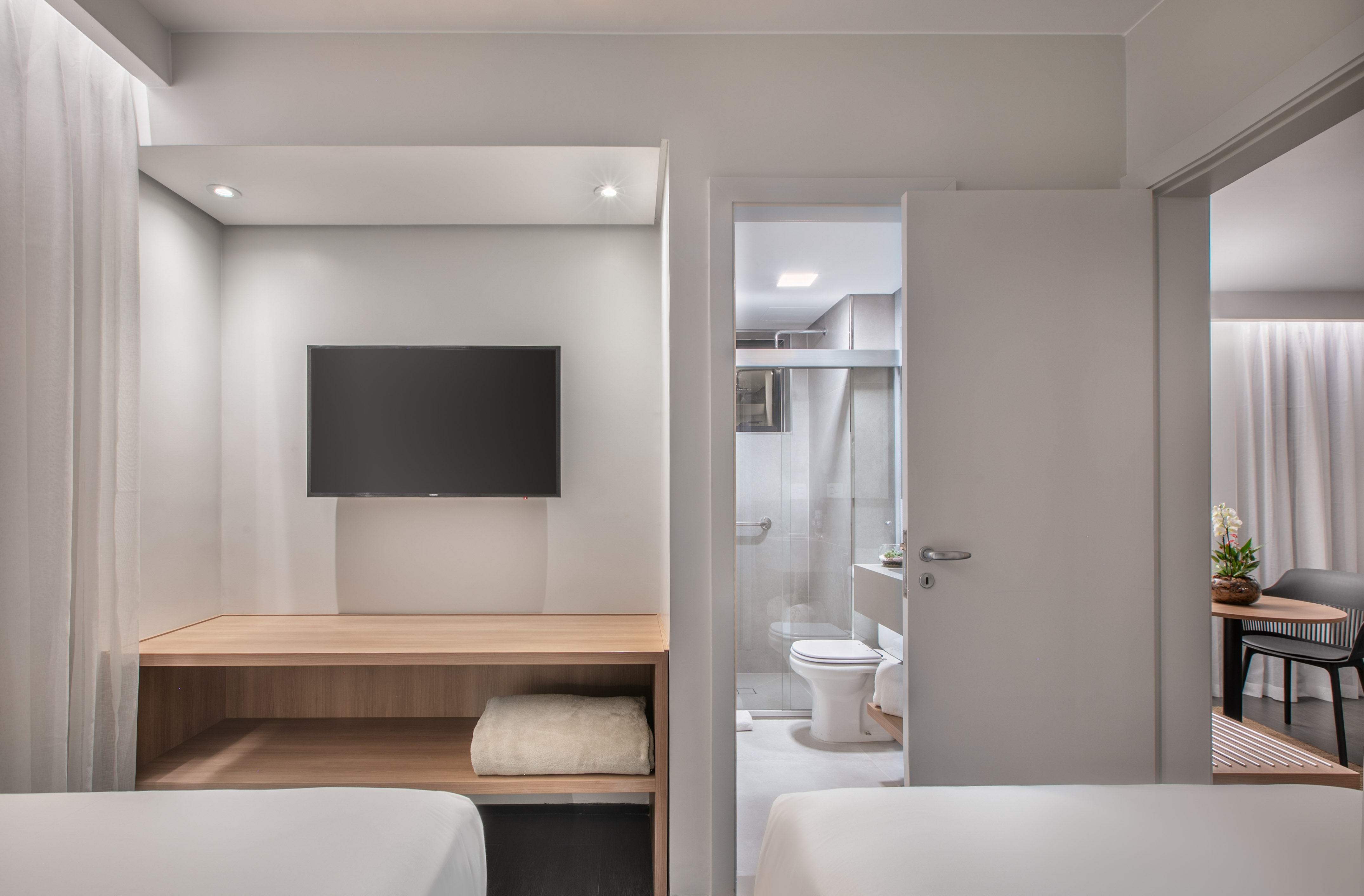 Clean modern hotel room with TV, wooden desk, and ensuite bathroom.