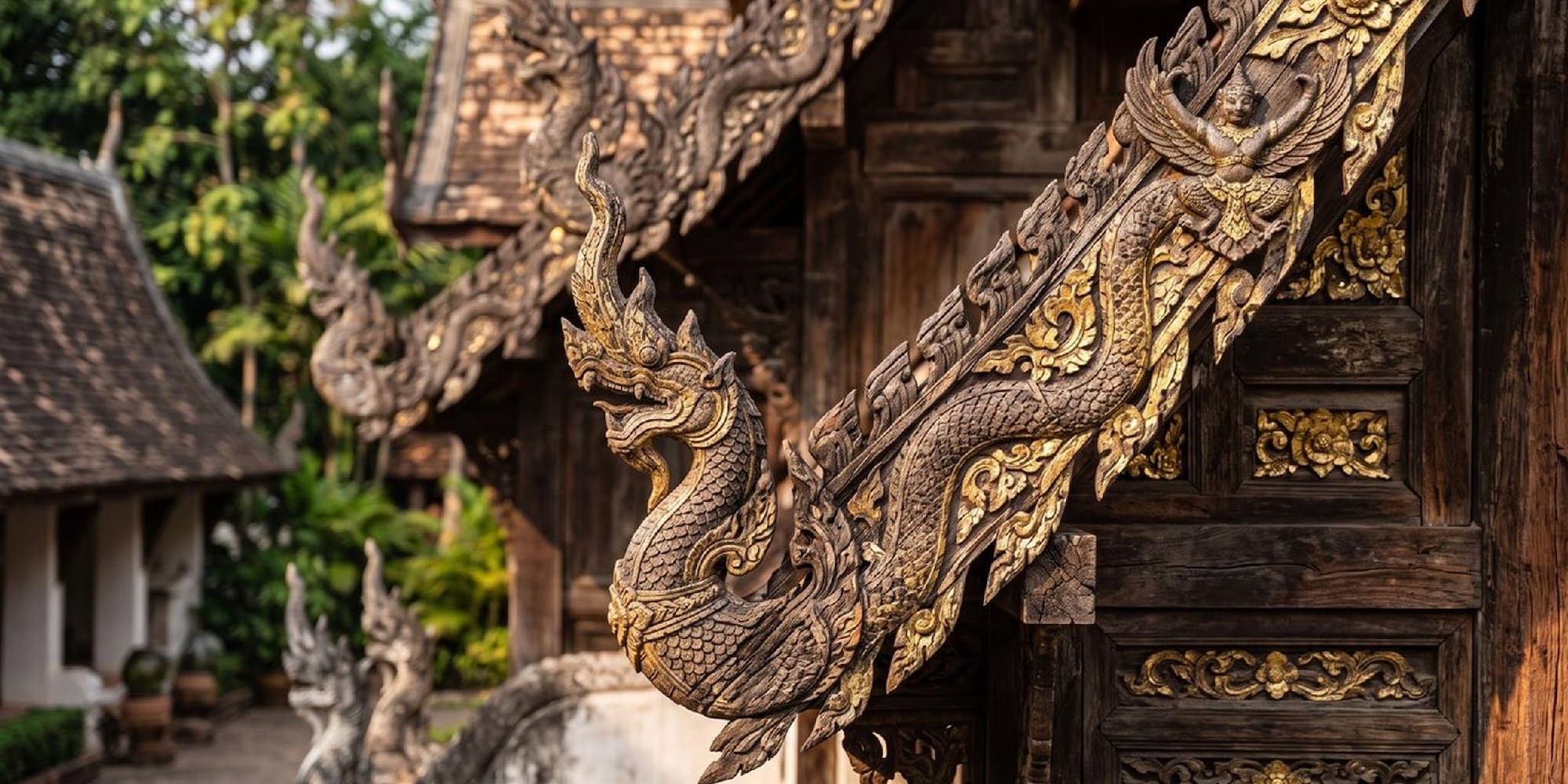 Golden Naga and Garuda carvings adorn a traditional Thai temple roof.