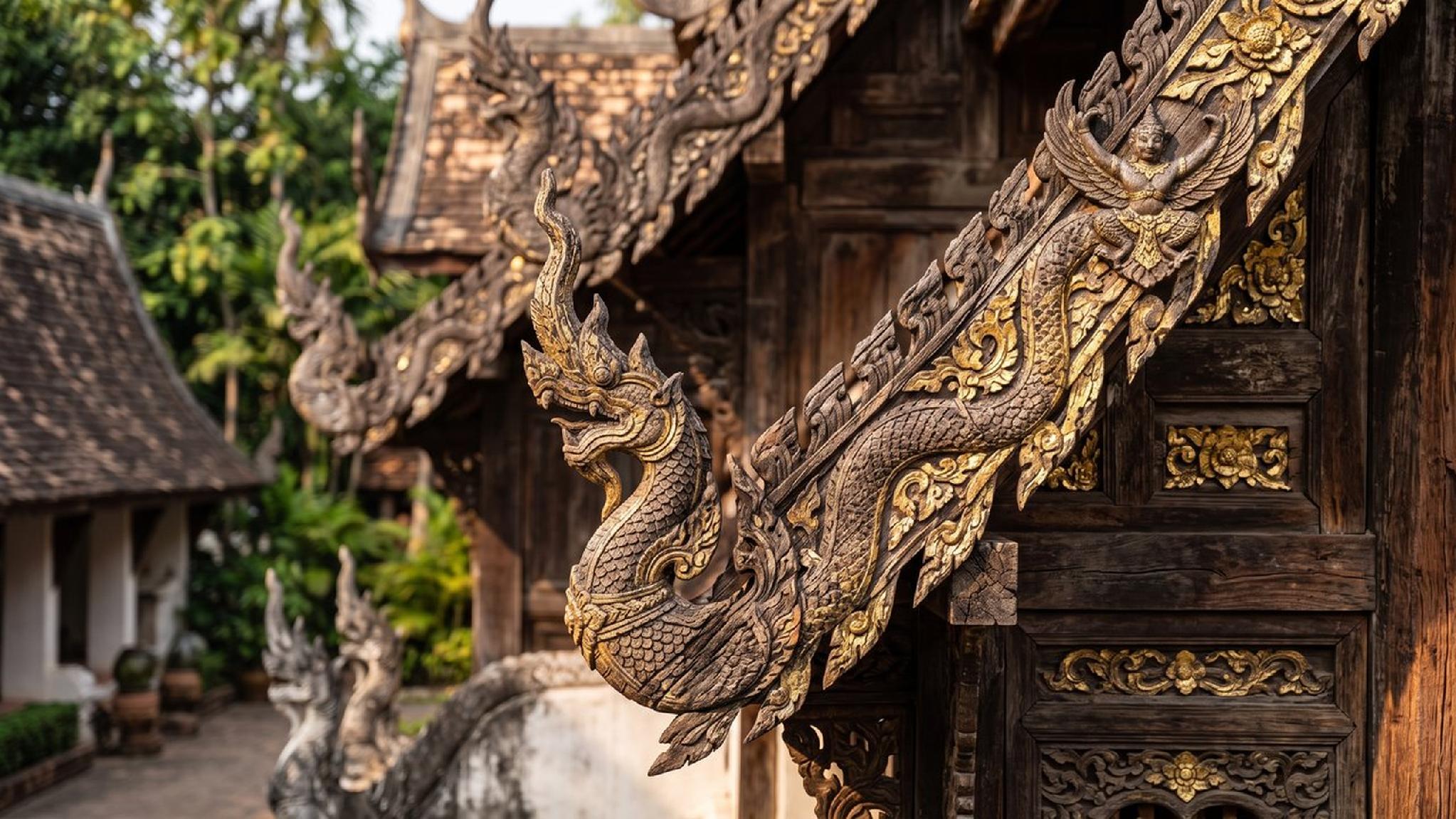 Golden Naga and Garuda carvings adorn a traditional Thai temple roof.