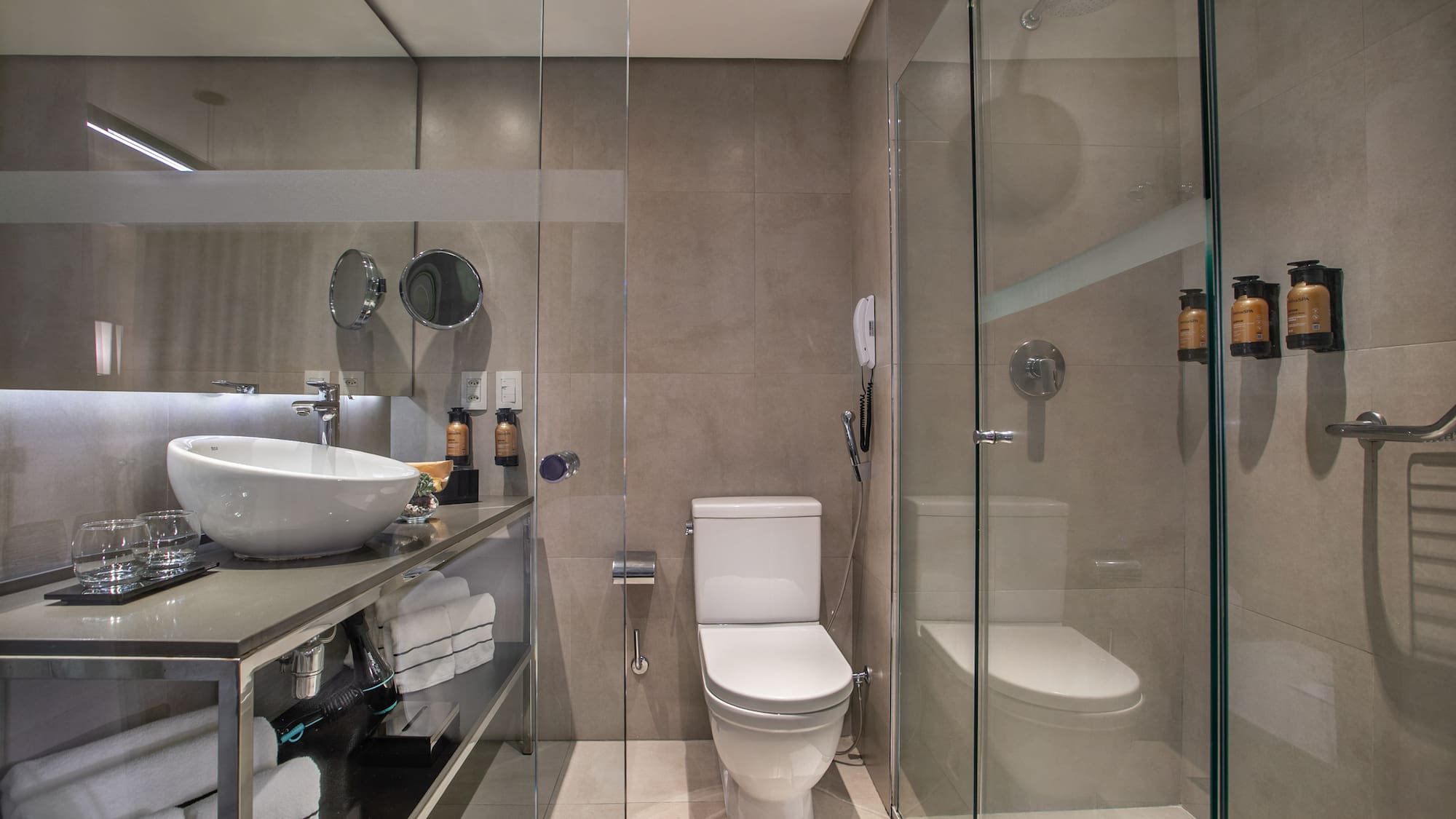 Banheiro moderno com pia sobreposta, vaso sanitário e box de vidro. - Grand Premium - Meliá Ibirapuera, São Paulo