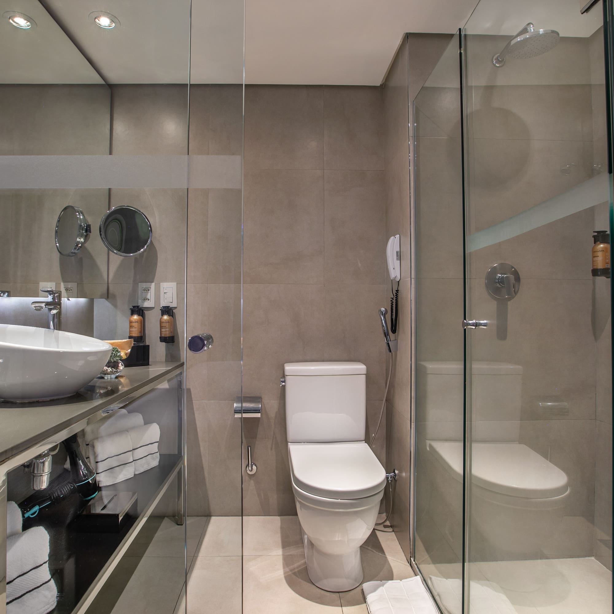 Banheiro moderno com pia sobreposta, vaso sanitário e box de vidro. - Grand Premium - Meliá Ibirapuera, São Paulo