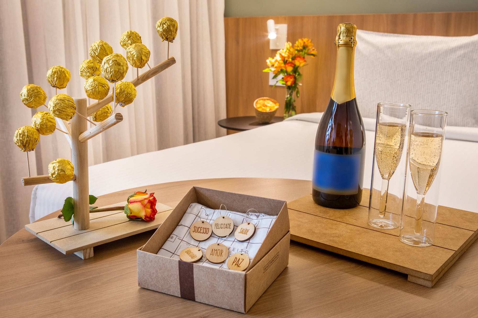 Celebración en hotel: champán, copas, bombones, rosa y etiquetas con deseos.