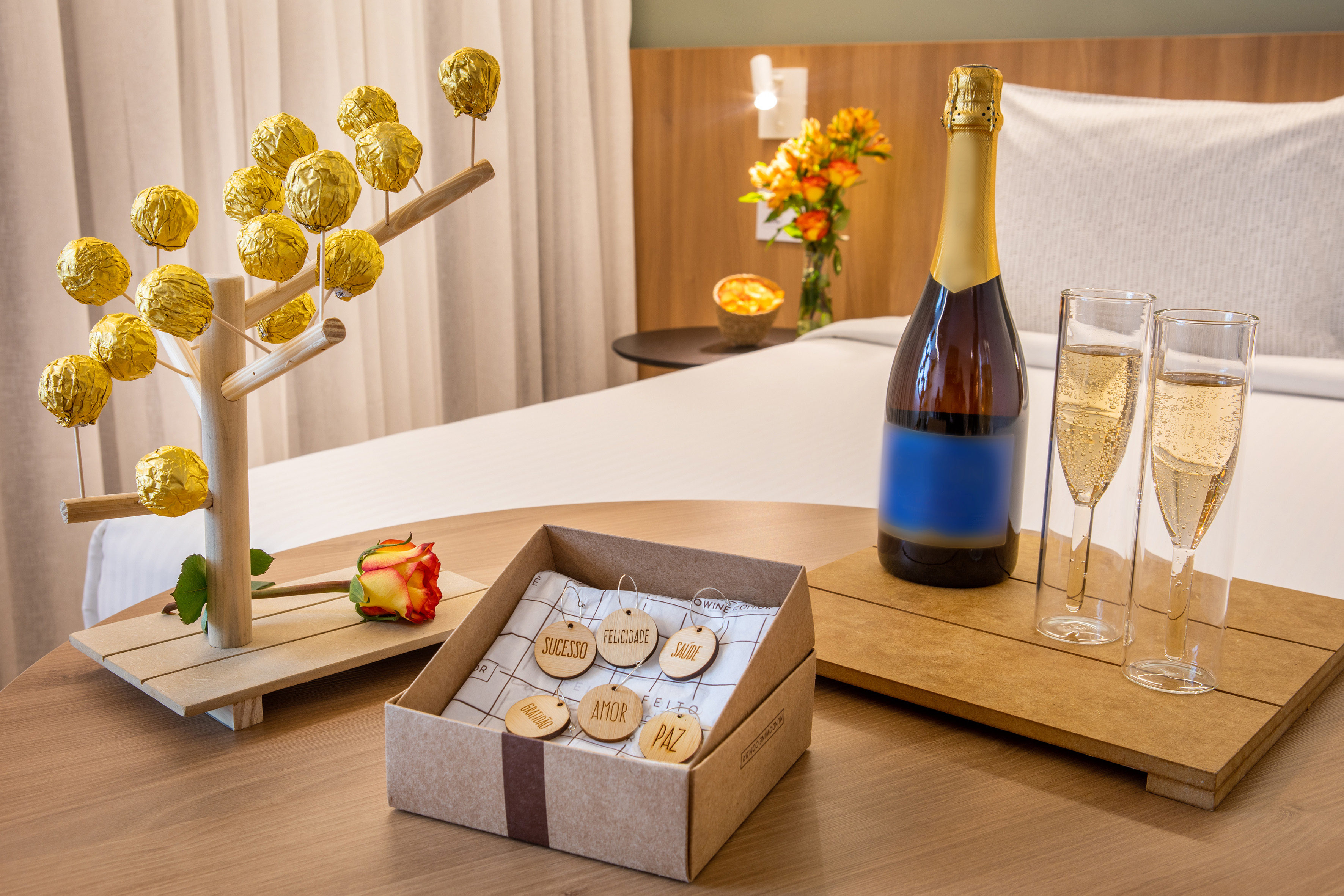 Celebración en hotel: champán, copas, bombones, rosa y etiquetas con deseos.