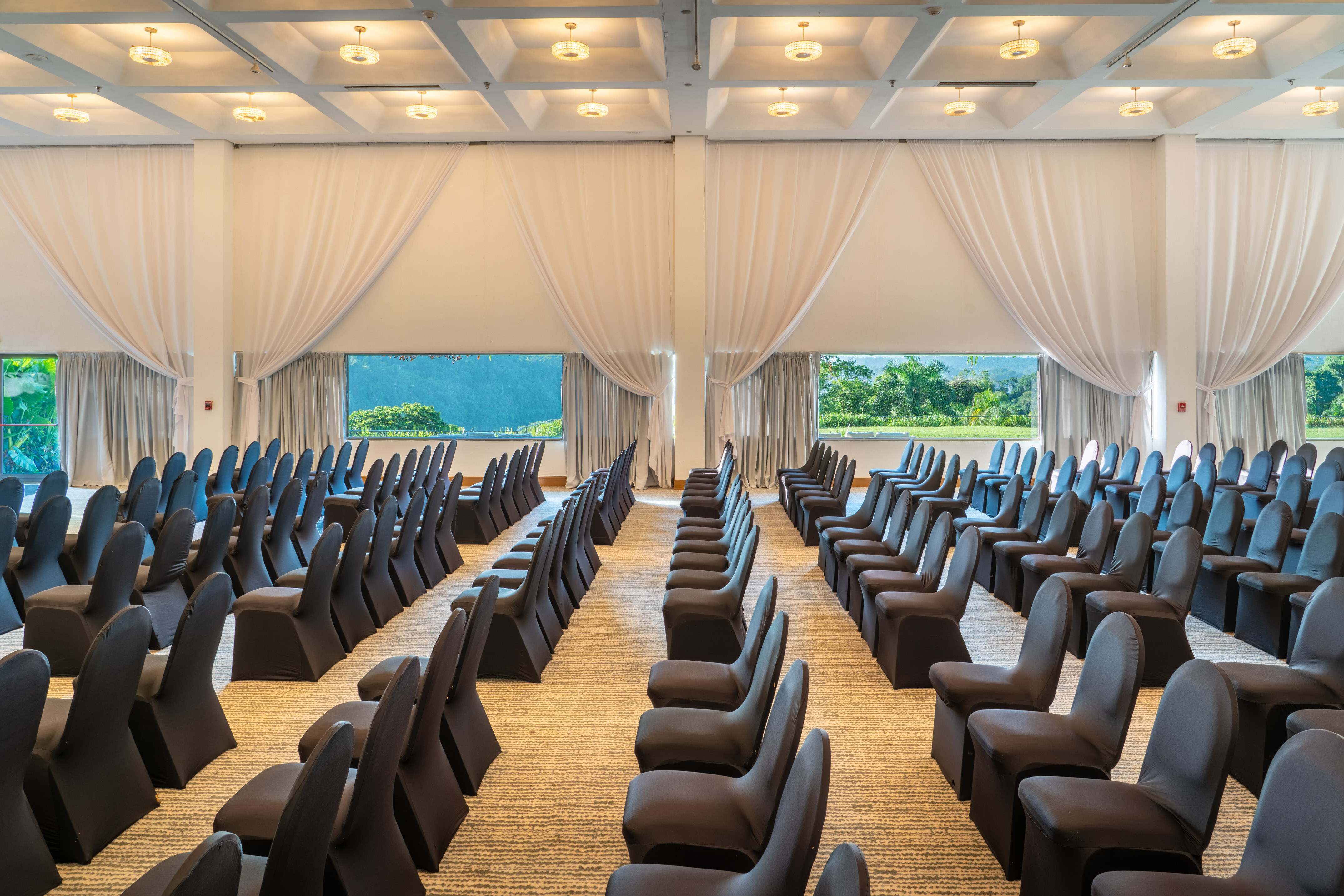 Large conference room setup with black chairs, windows, and outdoor views.
