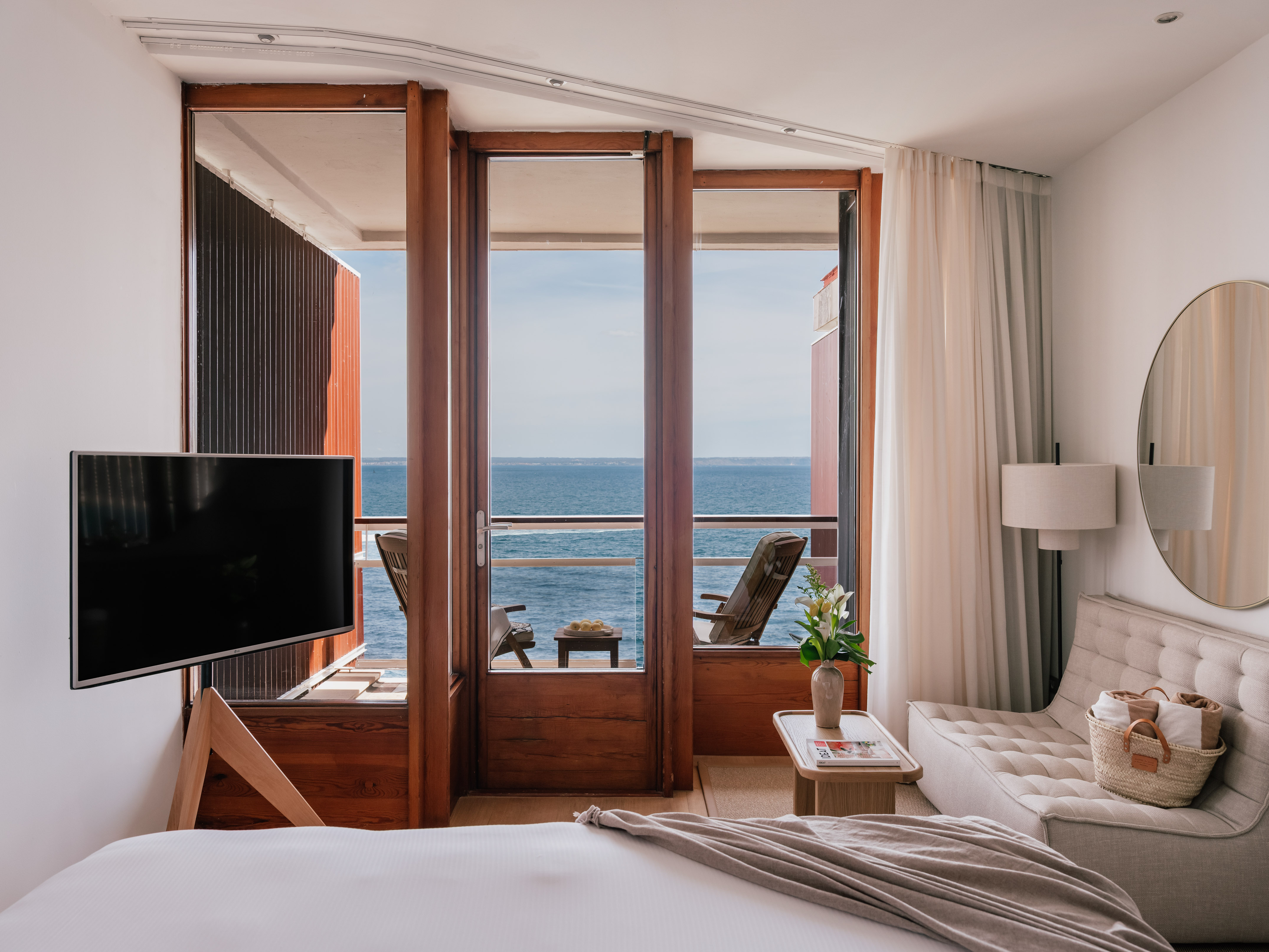 Oceanfront hotel bedroom with private balcony, bed, and comfortable sofa.