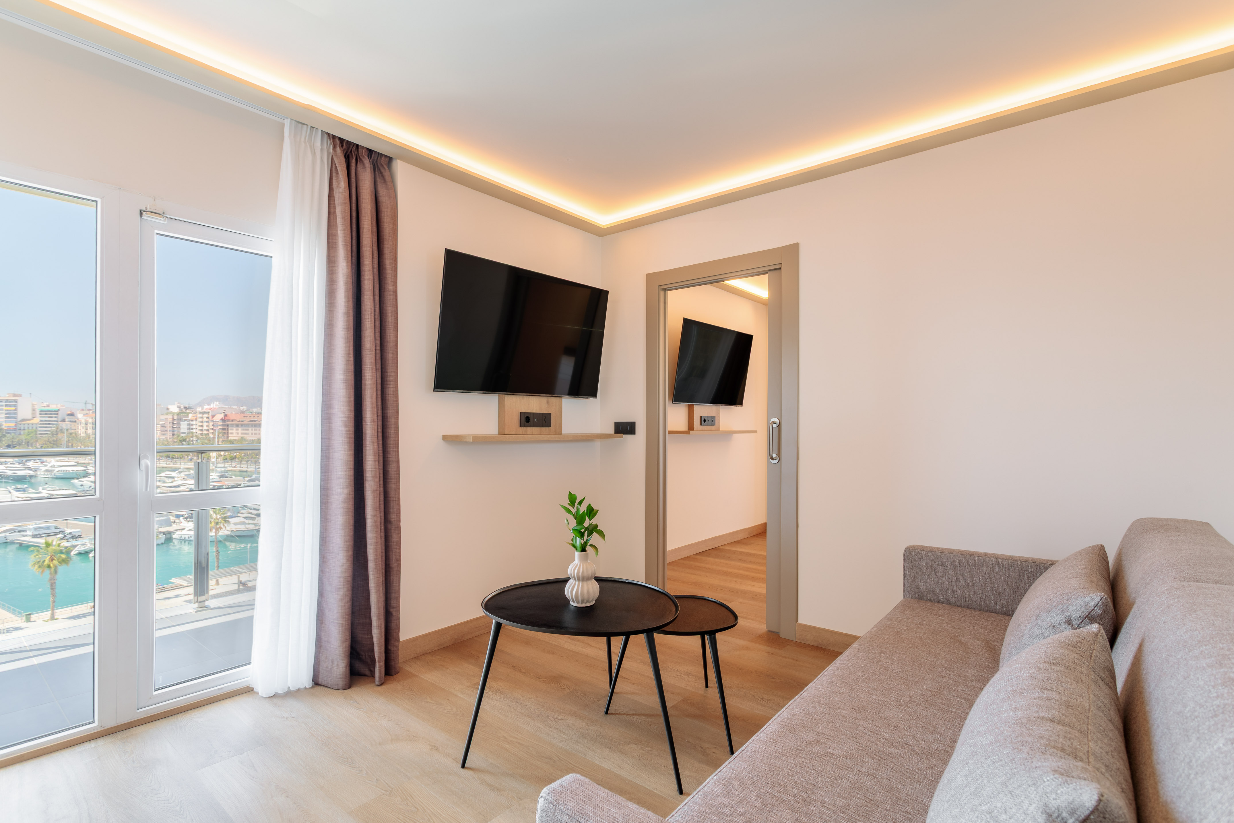 Modern living room with marina view balcony, sofa, and wall-mounted TV.