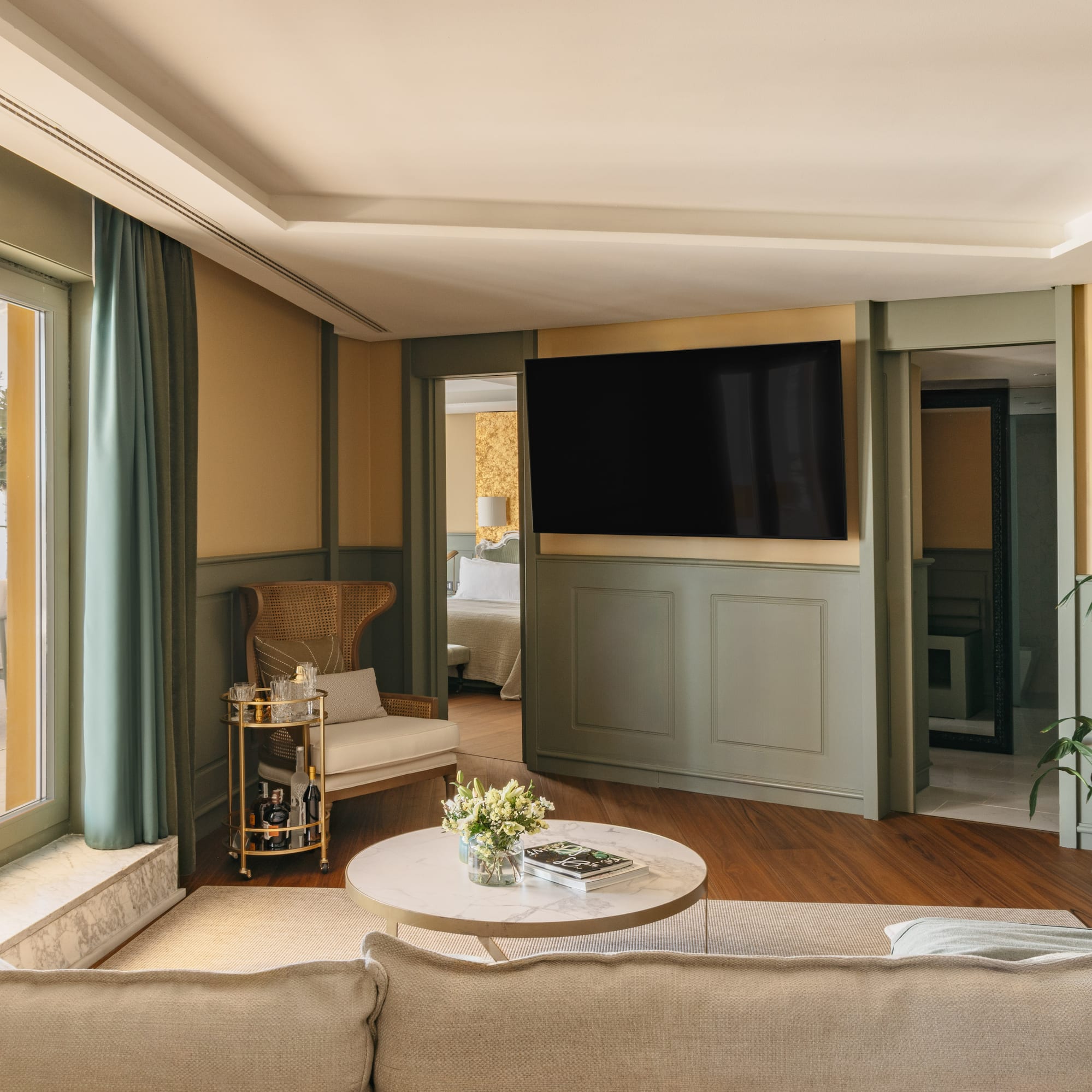Salón moderno en suite hotelera con TV, sofá, terraza y dormitorio.