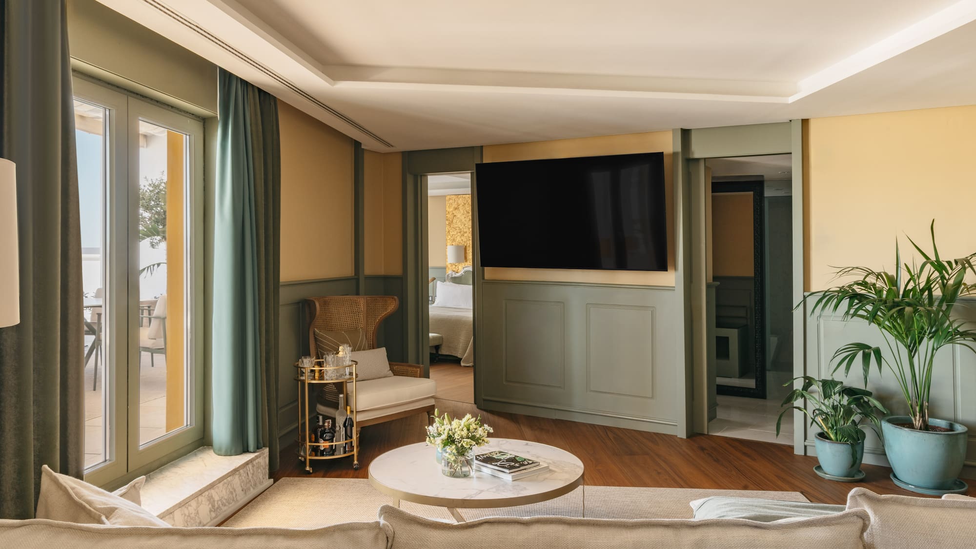Salón moderno en suite hotelera con TV, sofá, terraza y dormitorio.