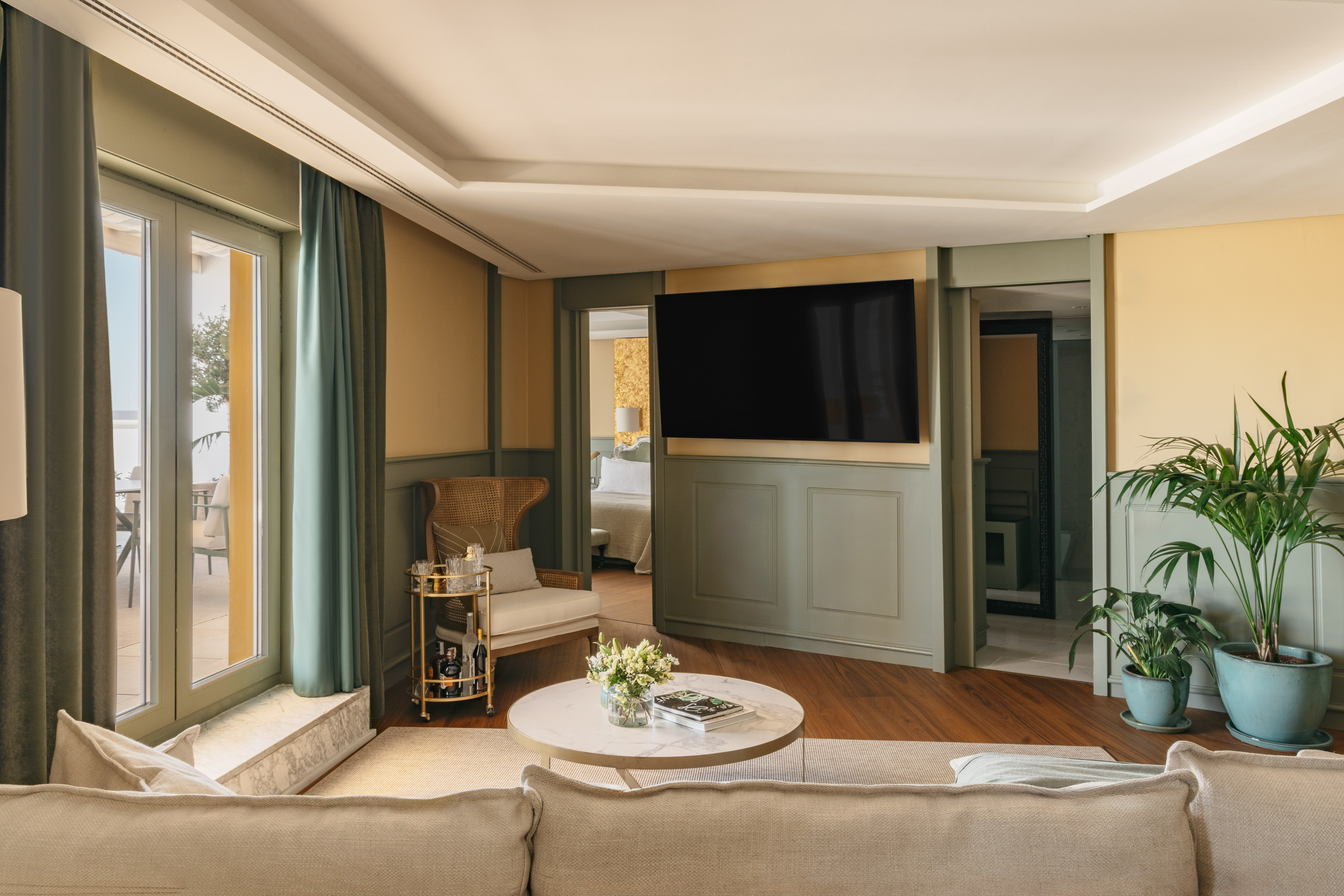 Salón moderno en suite hotelera con TV, sofá, terraza y dormitorio.