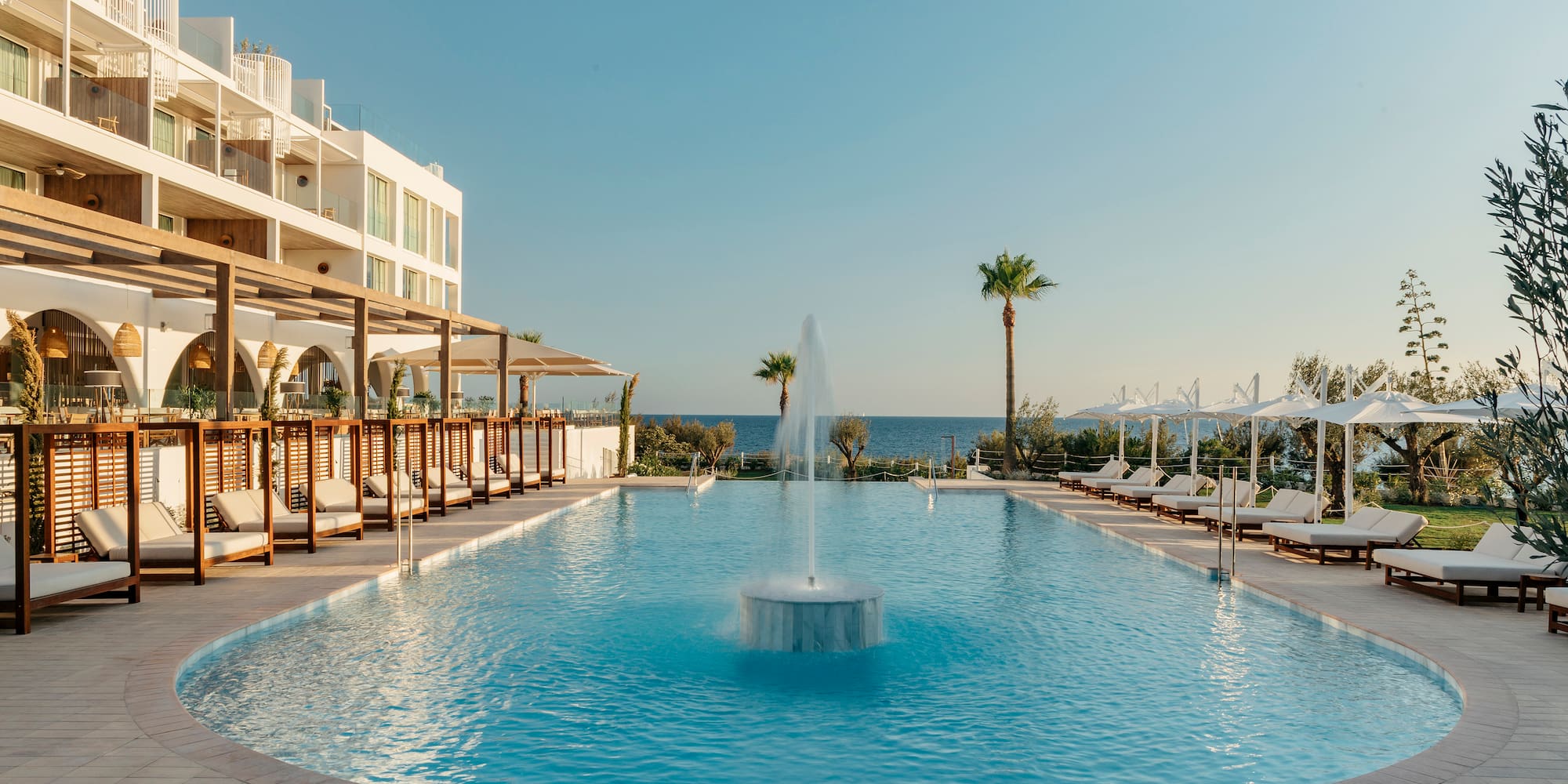 a pool with a fountain and chairs around it