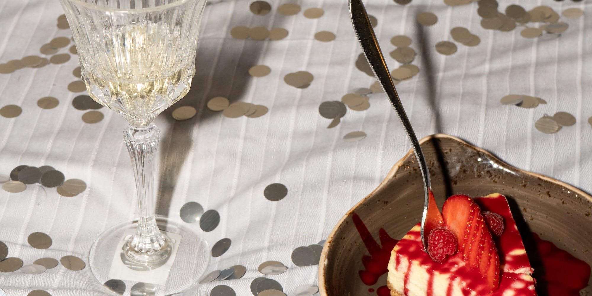 a slice of cake with strawberries and a glass of wine