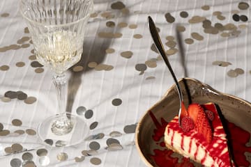 a slice of cake with strawberries and a glass of wine