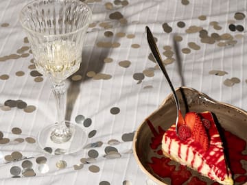a slice of cake with strawberries and a glass of wine