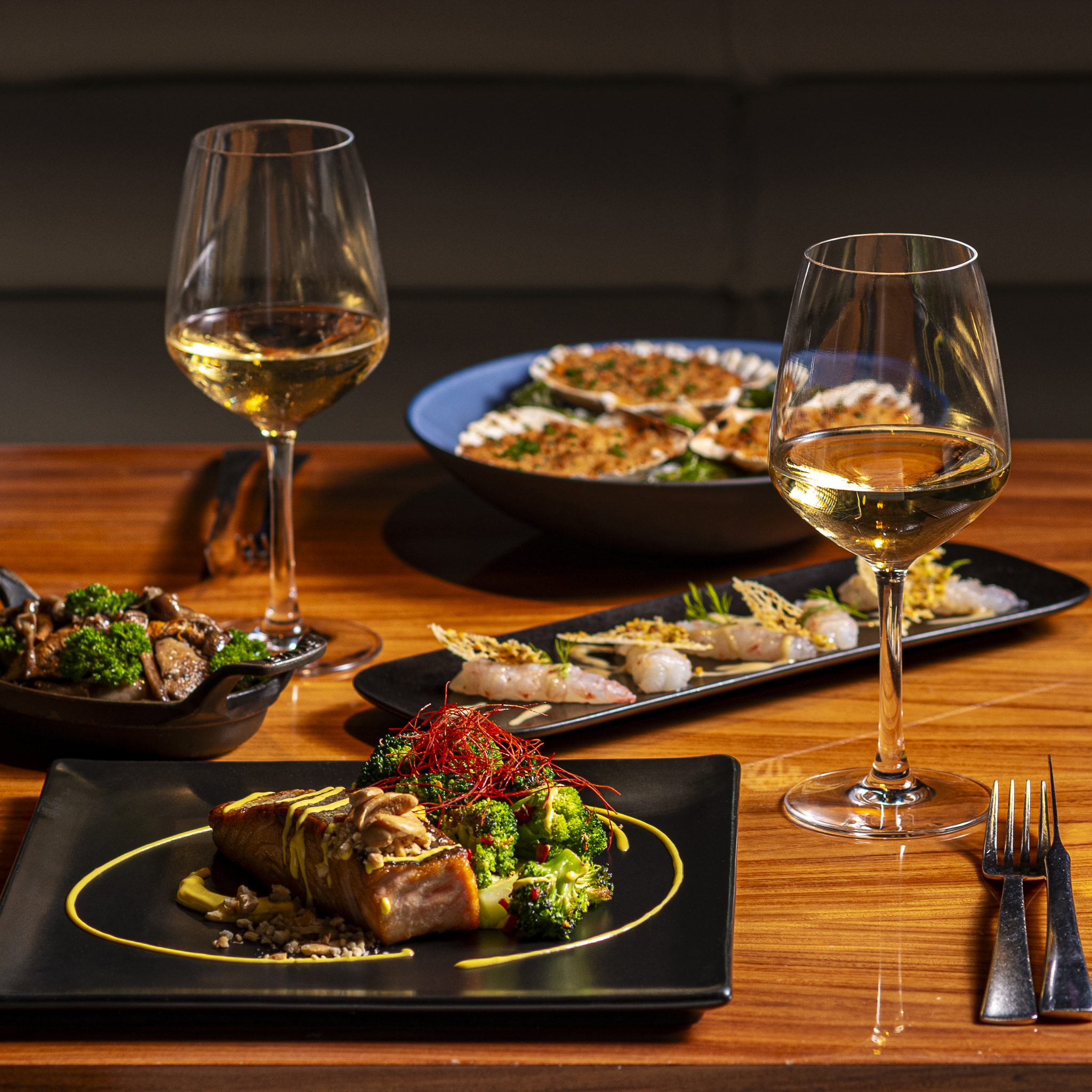 Fine dining with seared salmon, scallops, shrimp, and white wine glasses.