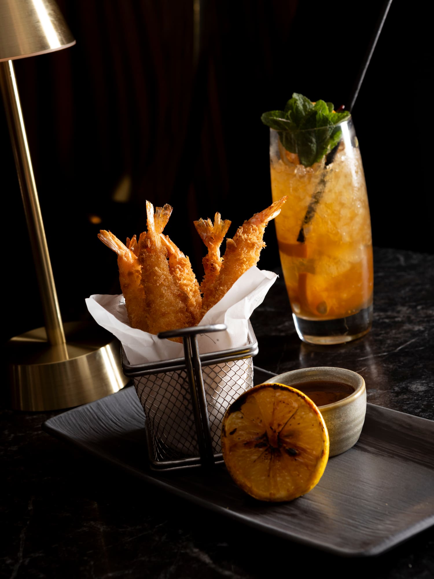 a fried shrimp in a basket next to a drink