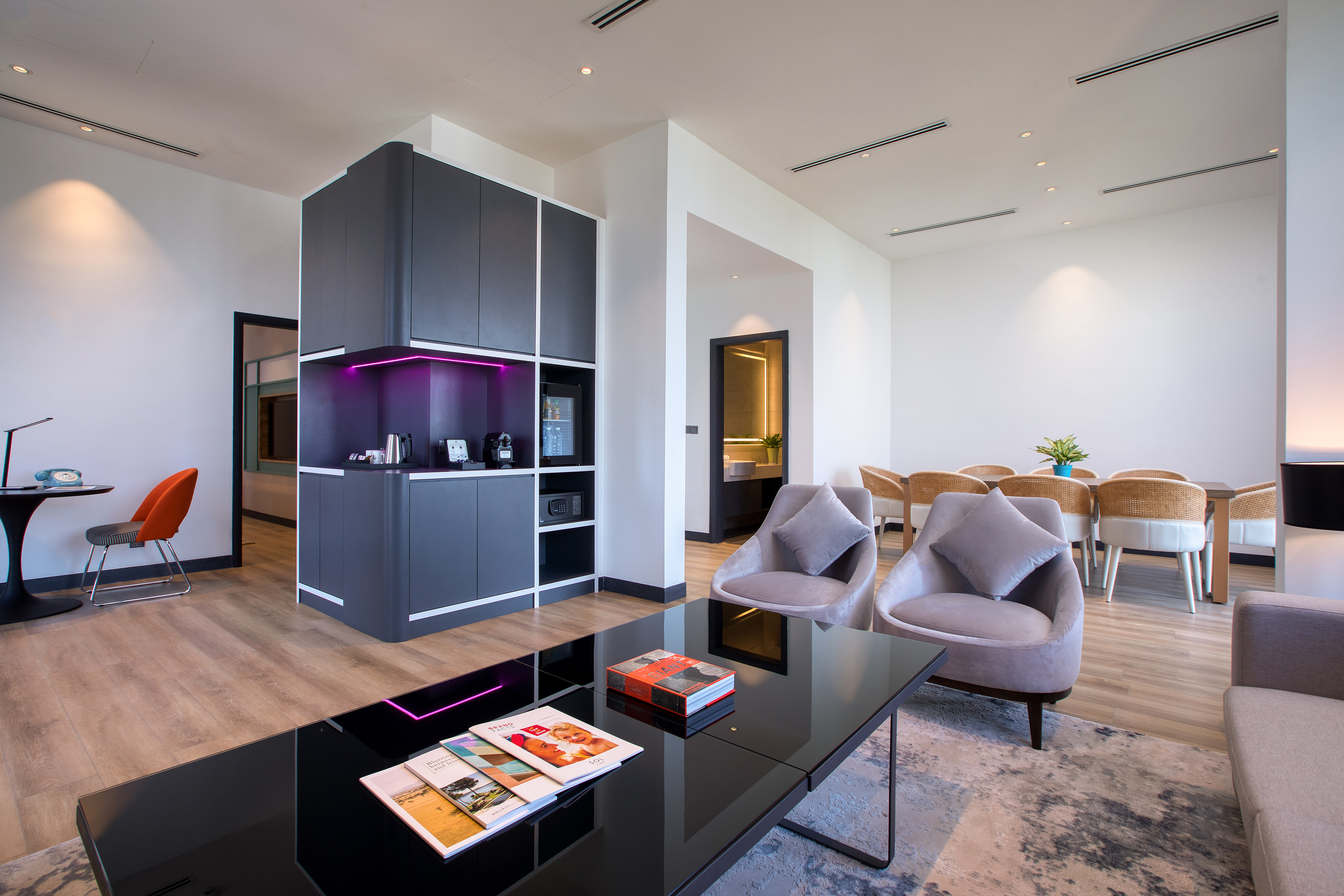 Stylish hotel suite living room with dining area and modern kitchenette.