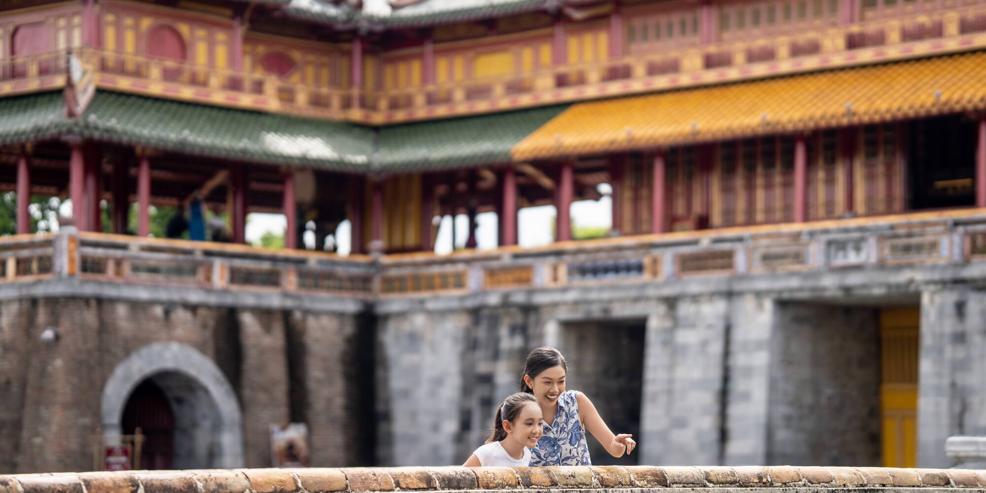 a woman and a girl standing on a wall in front of a building