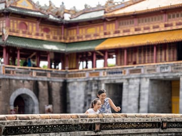 a woman and a girl standing on a wall in front of a building