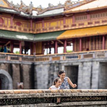 a woman and a girl standing on a wall in front of a building