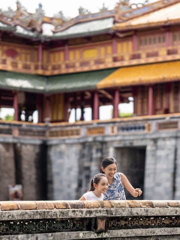 a woman and a girl standing on a wall in front of a building