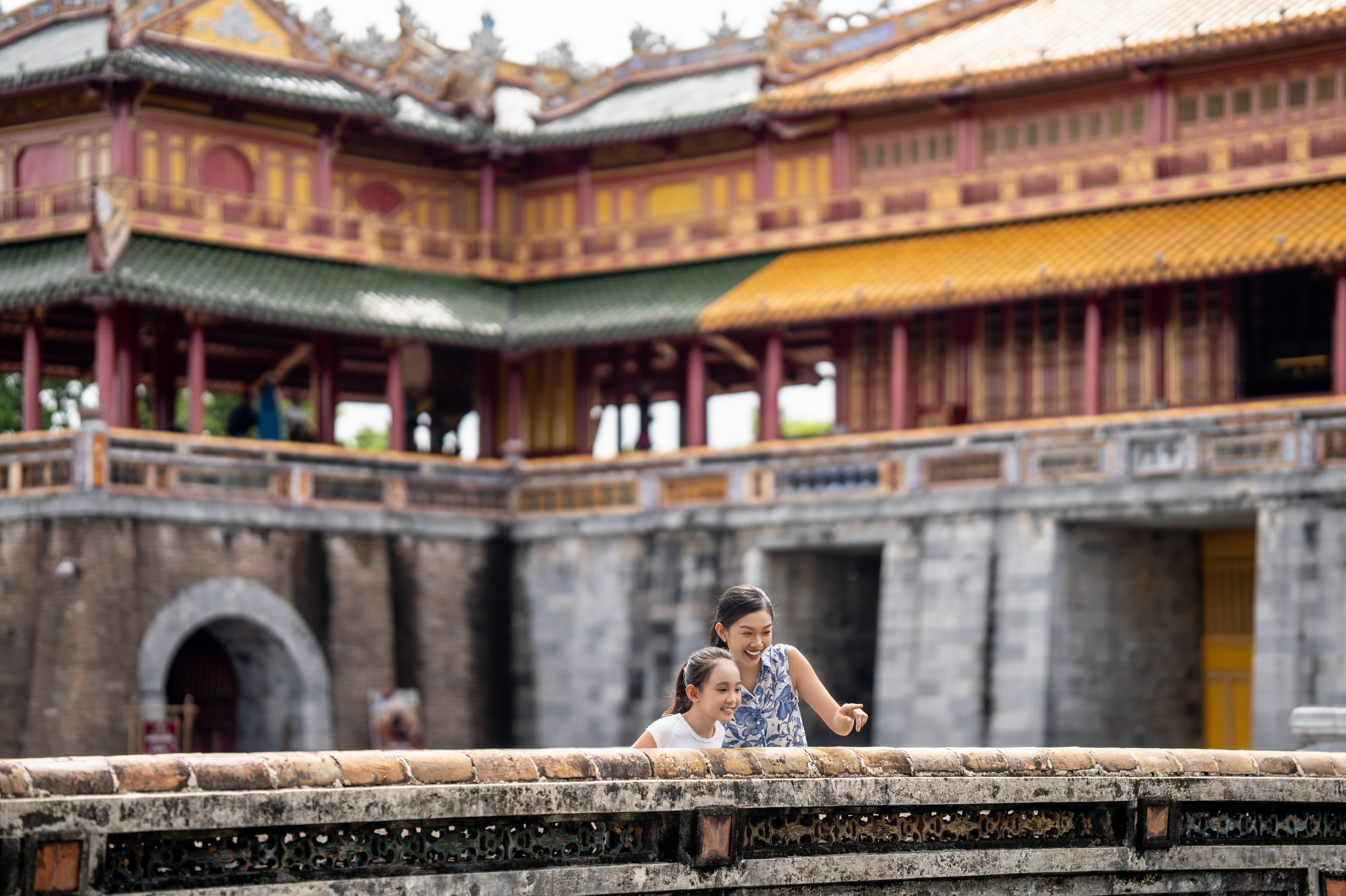 a woman and a girl standing on a wall in front of a building