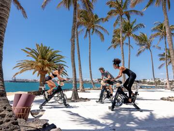 a group of people on exercise bikes by a body of water