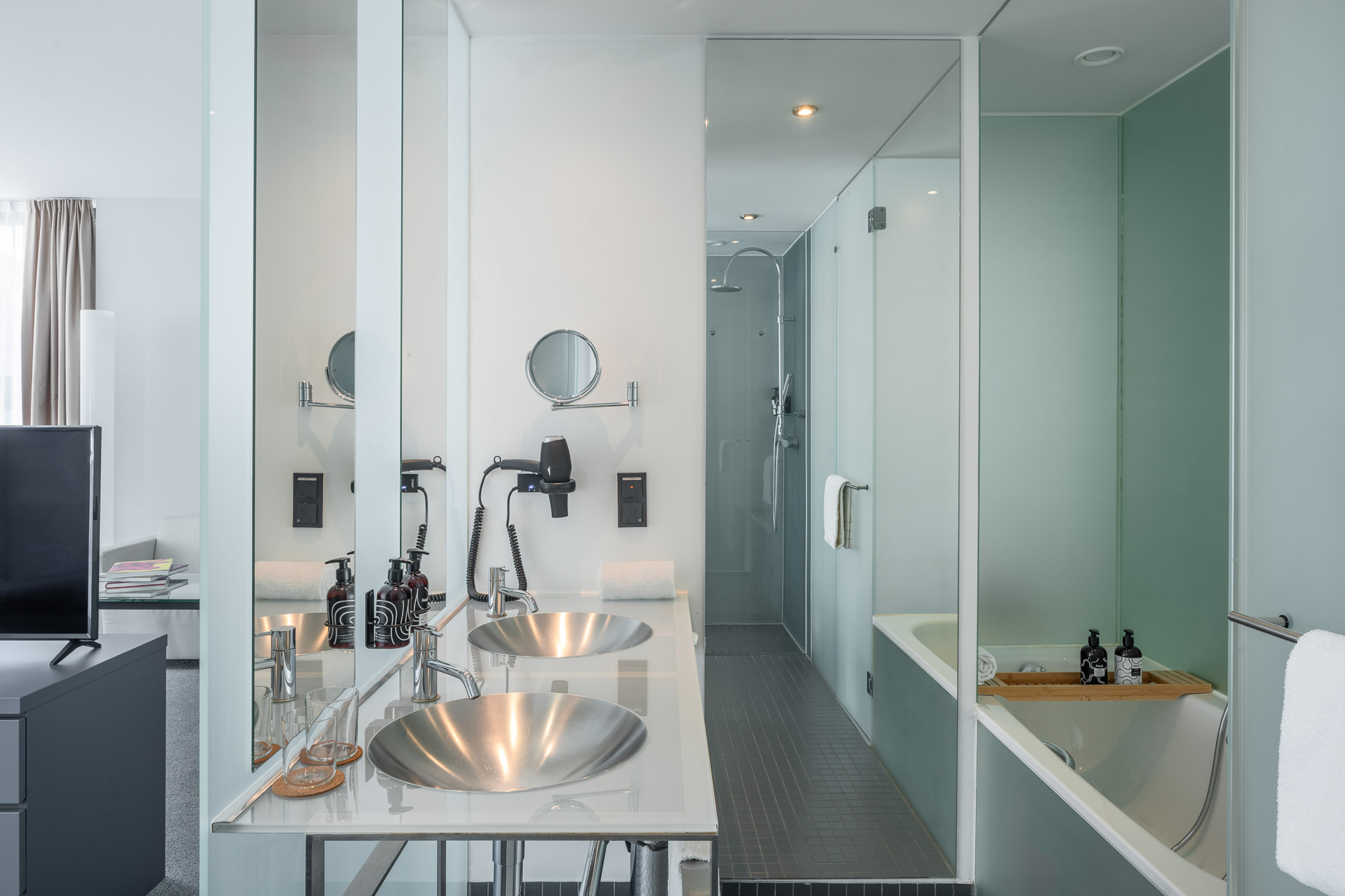 Sleek hotel bathroom featuring double vanity, glass shower, and built-in tub.