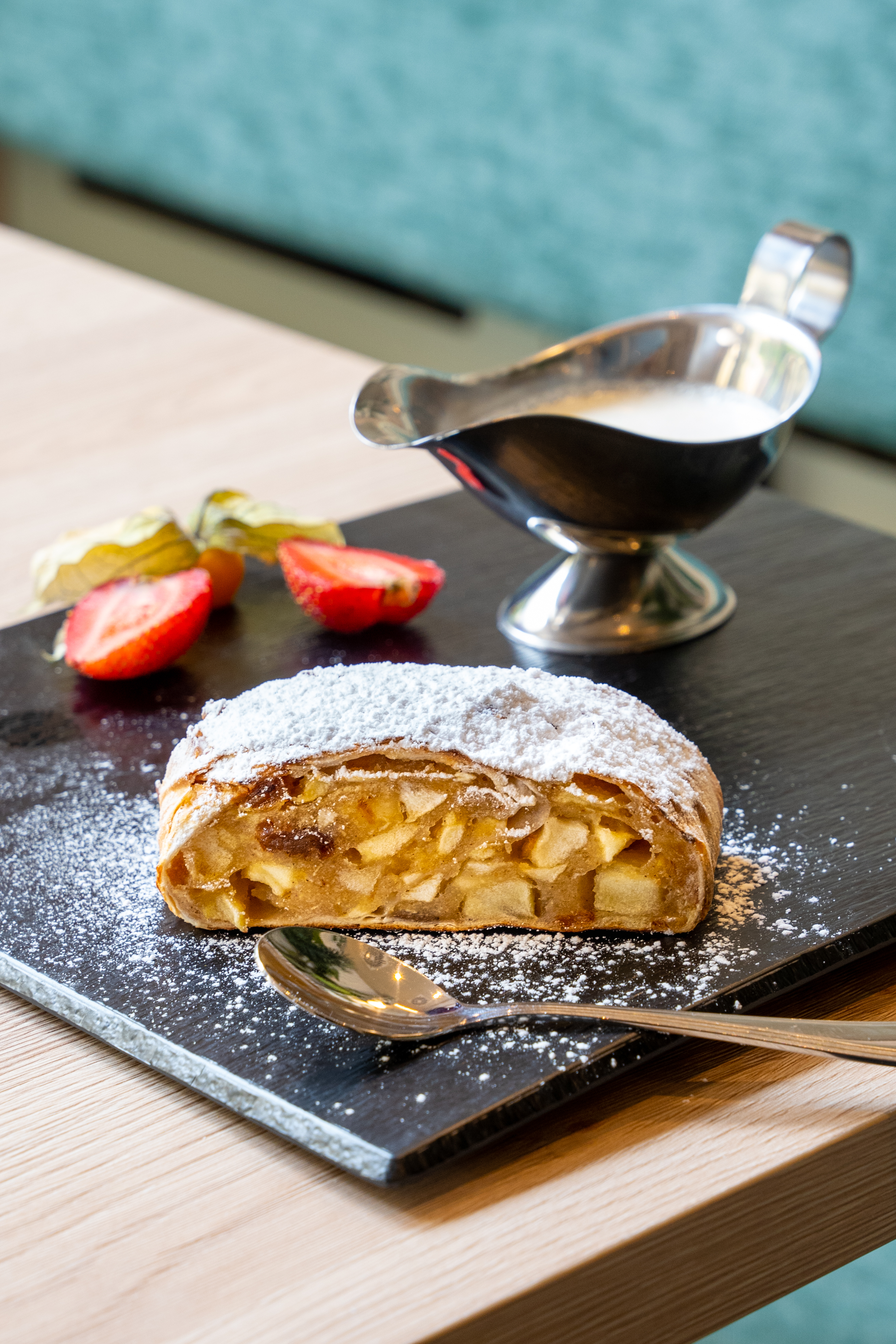 Apple strudel slice with powdered sugar, strawberries, physalis, cream sauce.