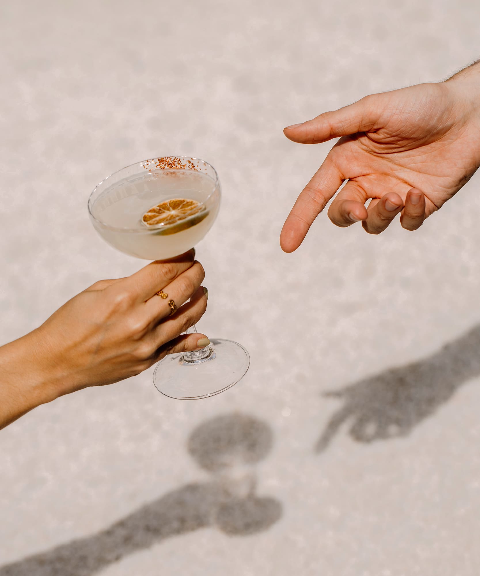 Manos con cóctel margarita, rodaja de lima y borde de chile. Sombra de brindis.