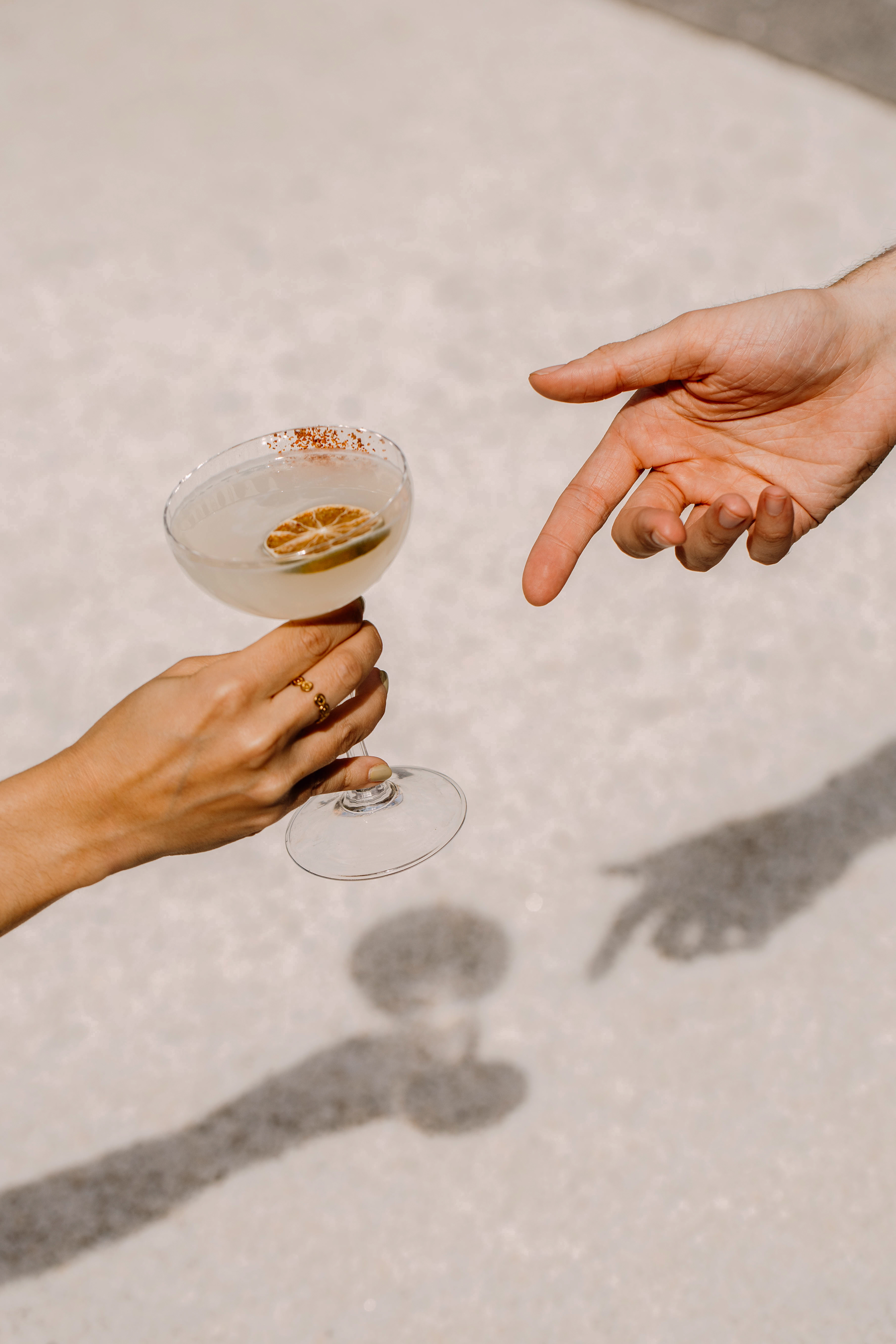 Female hand holding spicy cocktail with lime, male hand pointing at drink.