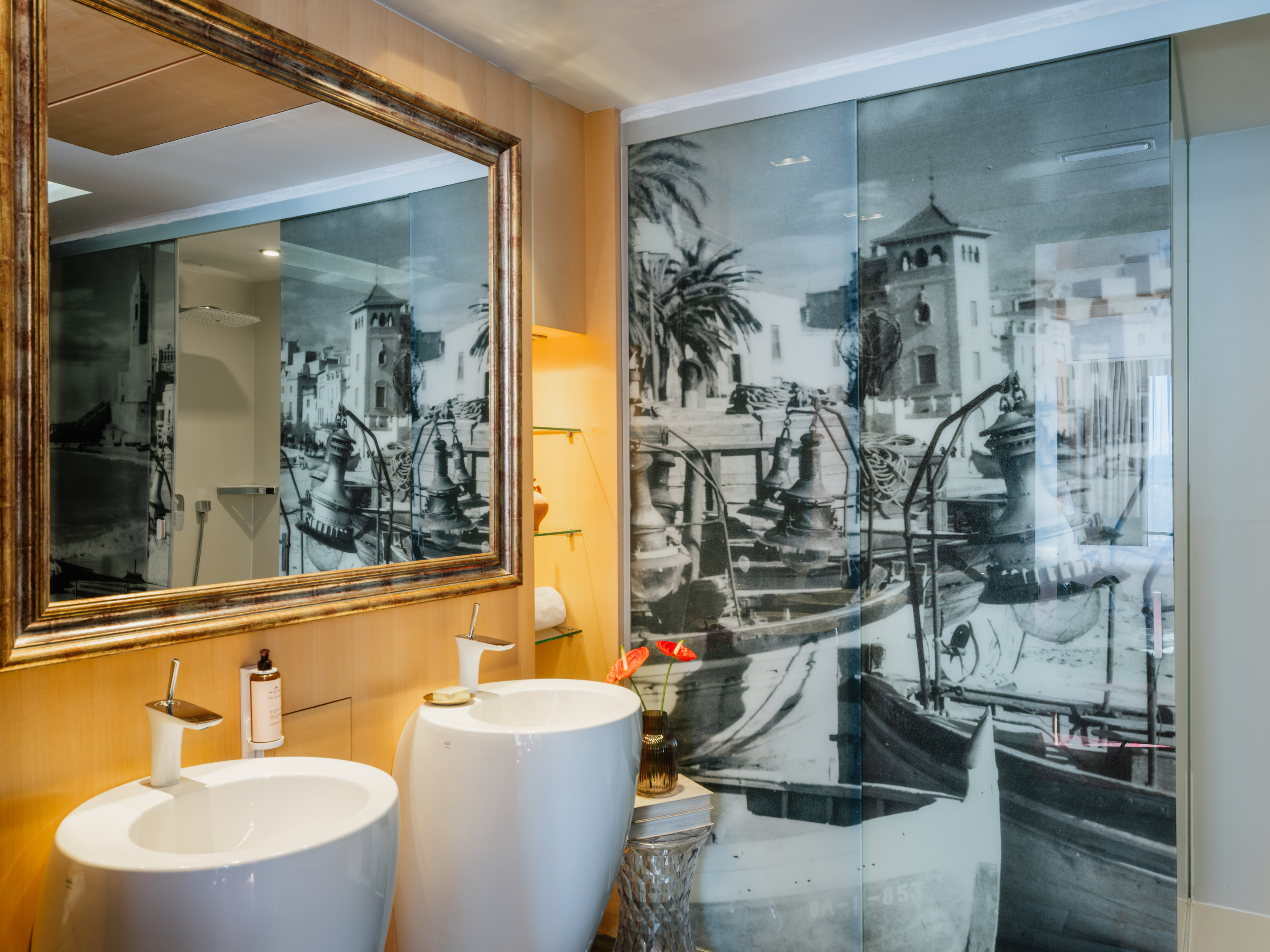 Modern bathroom with dual sinks, ornate mirror, and coastal glass shower.