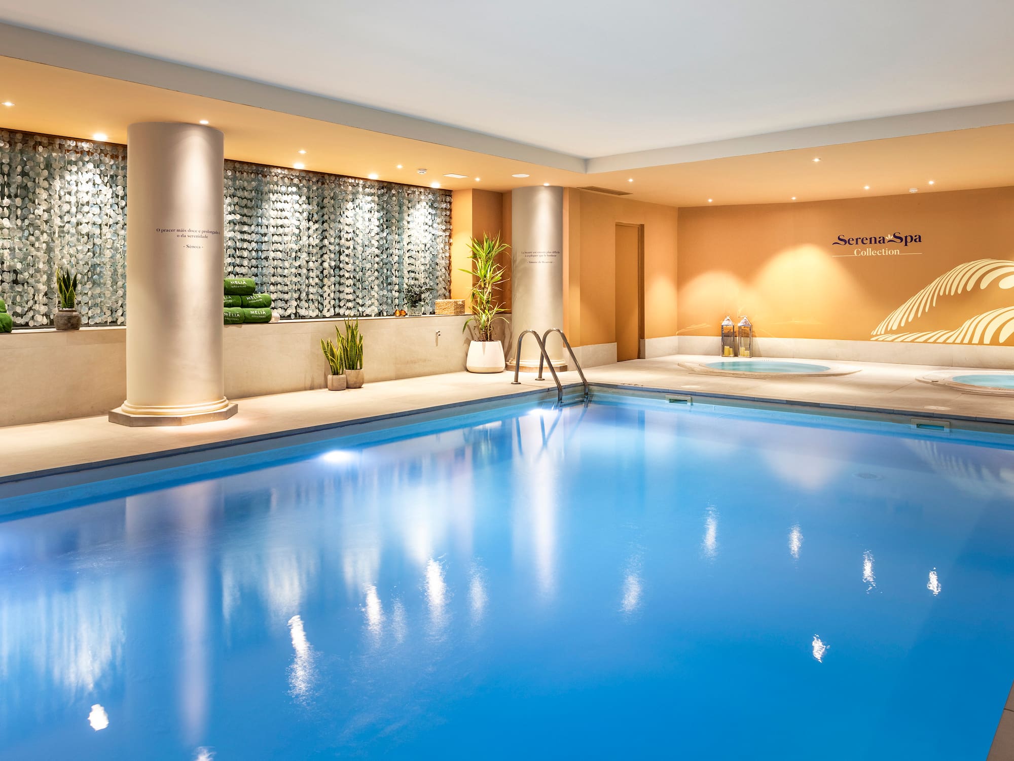 Luxurious indoor spa pool with two jacuzzis and soft lighting.