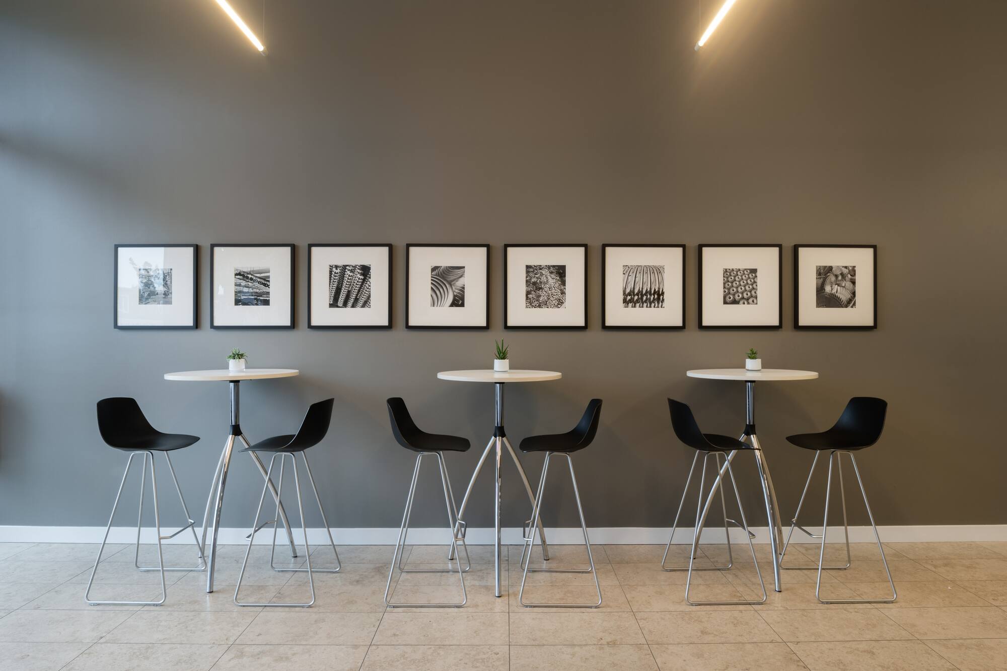 Modern office high-top tables with black stools and framed wall art.