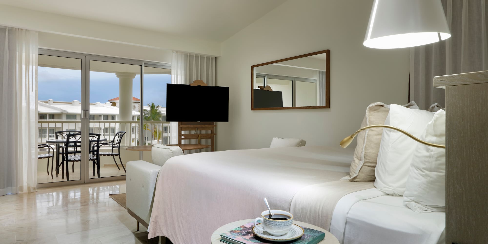 a bedroom with a bed and a table with a television and a glass door