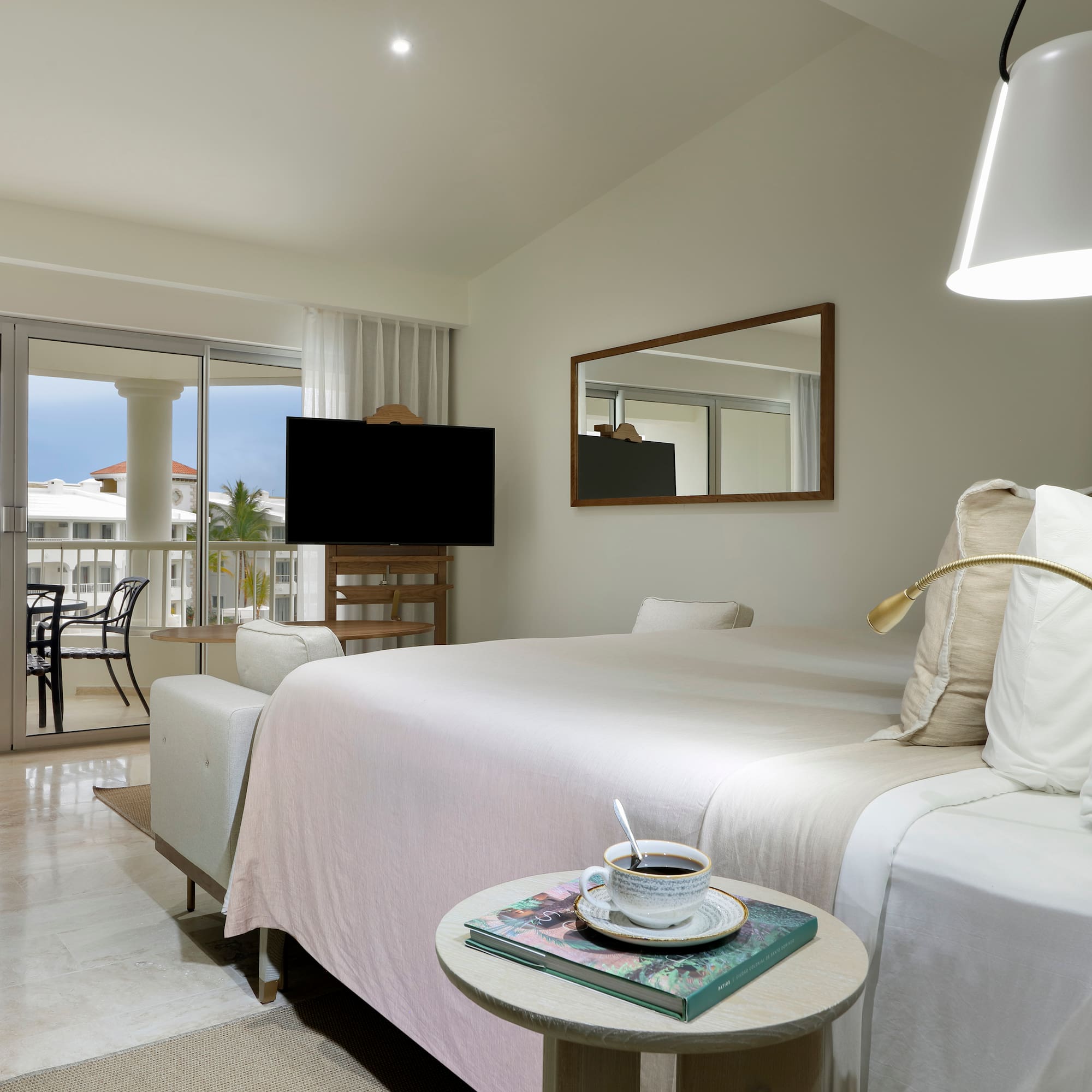 a bedroom with a bed and a table with a television and a glass door