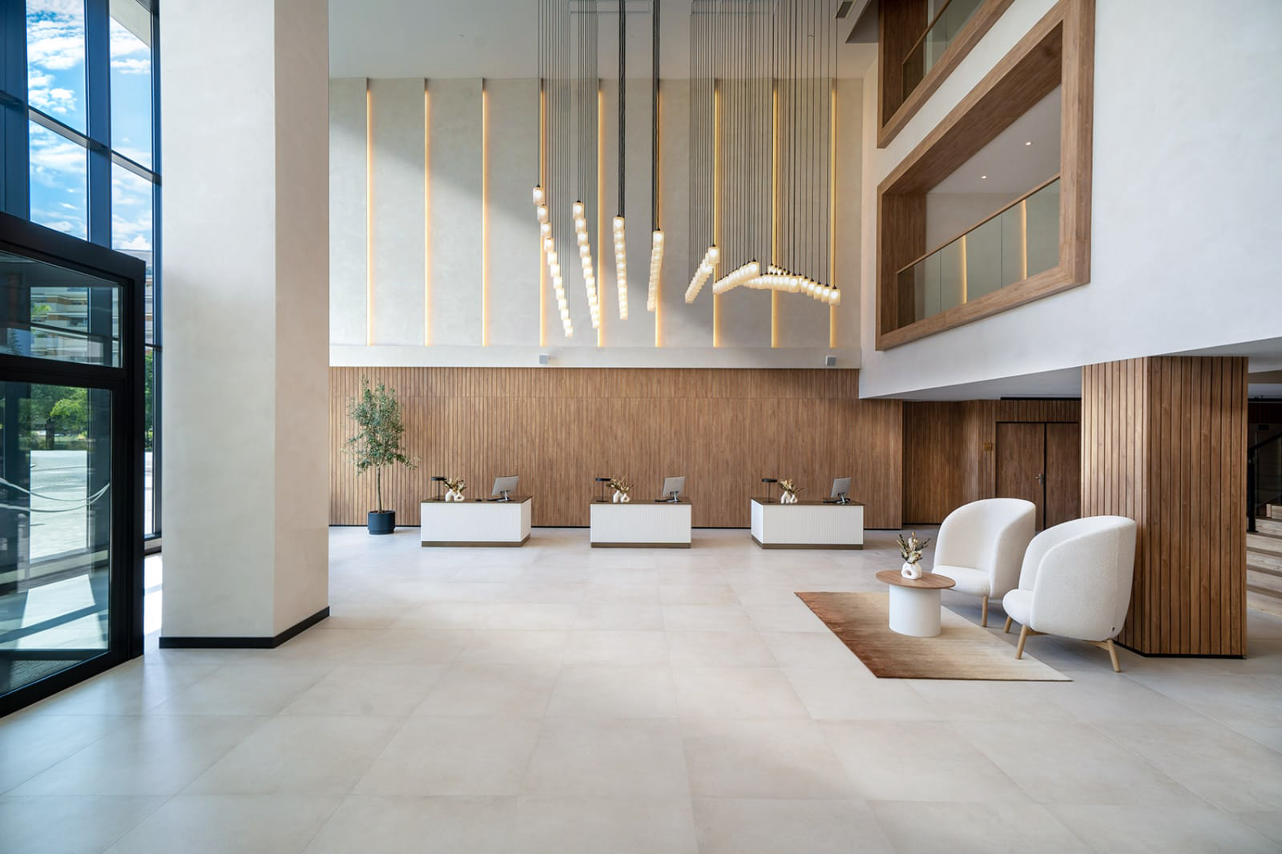 Modern hotel reception with three desks, wood walls, and modern chandeliers.