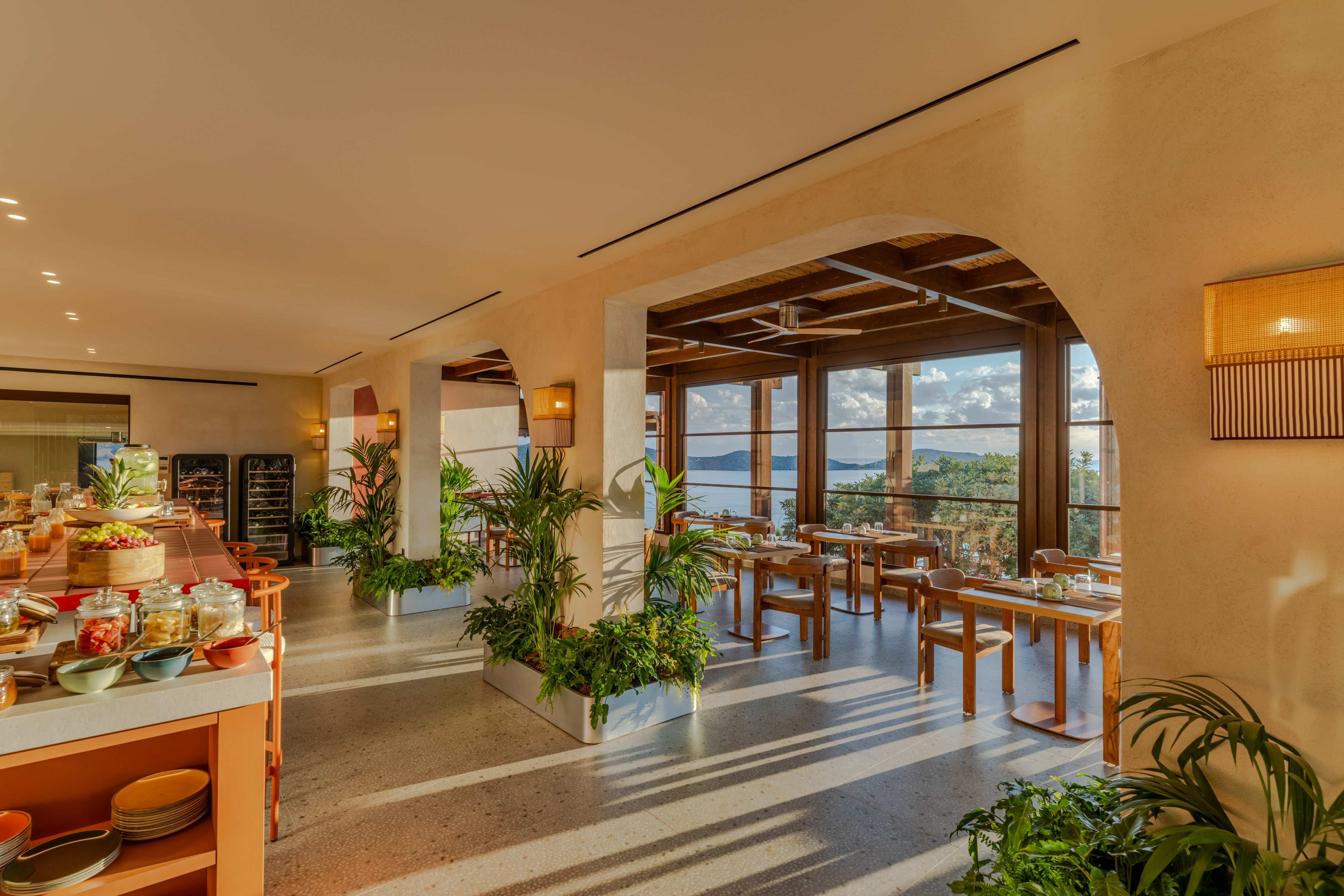 Sunny hotel restaurant with breakfast buffet and ocean view tables.