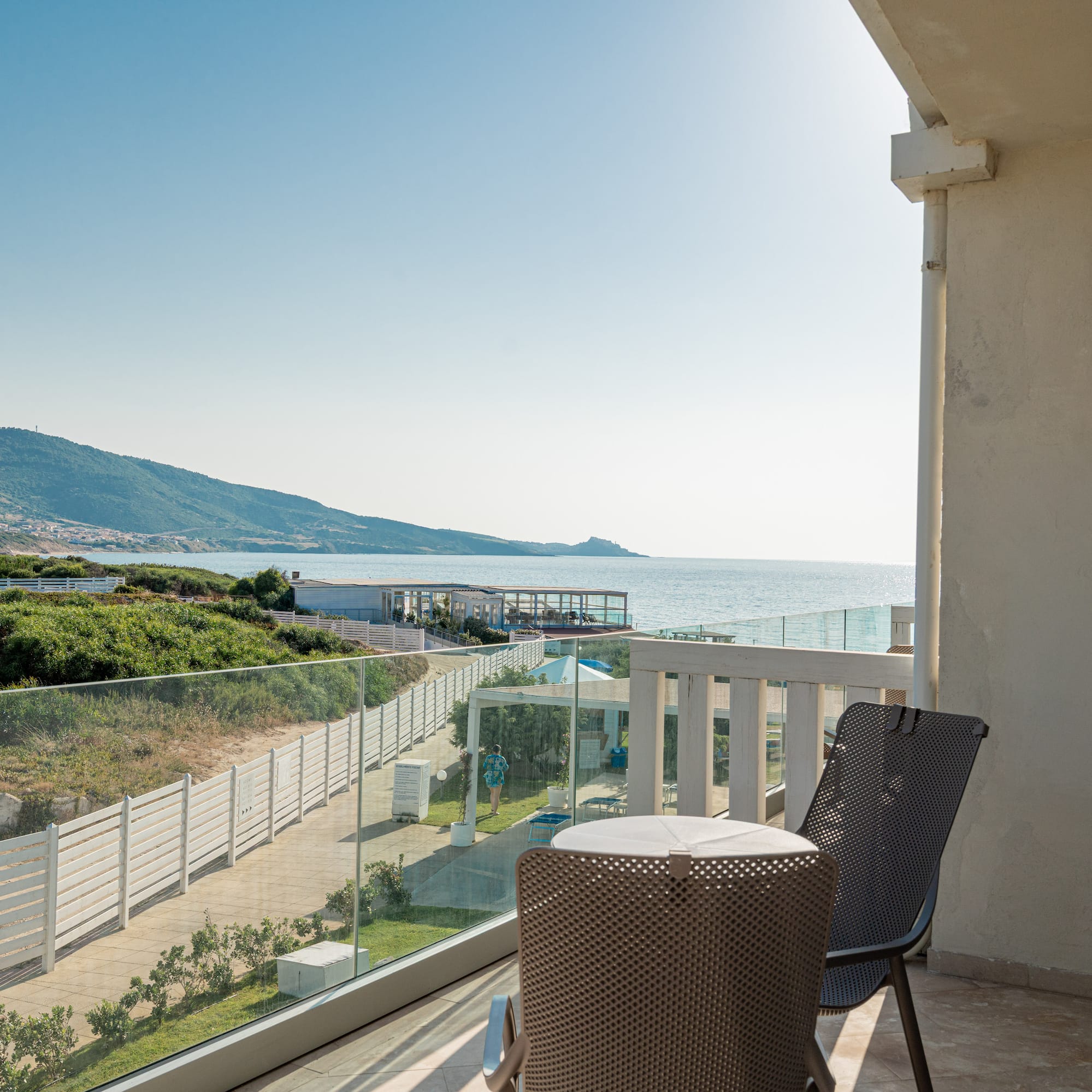 a chair and table on a balcony overlooking a body of water
