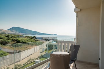 a chair and table on a balcony overlooking a body of water