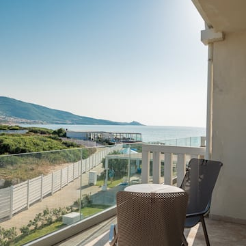 a chair and table on a balcony overlooking a body of water