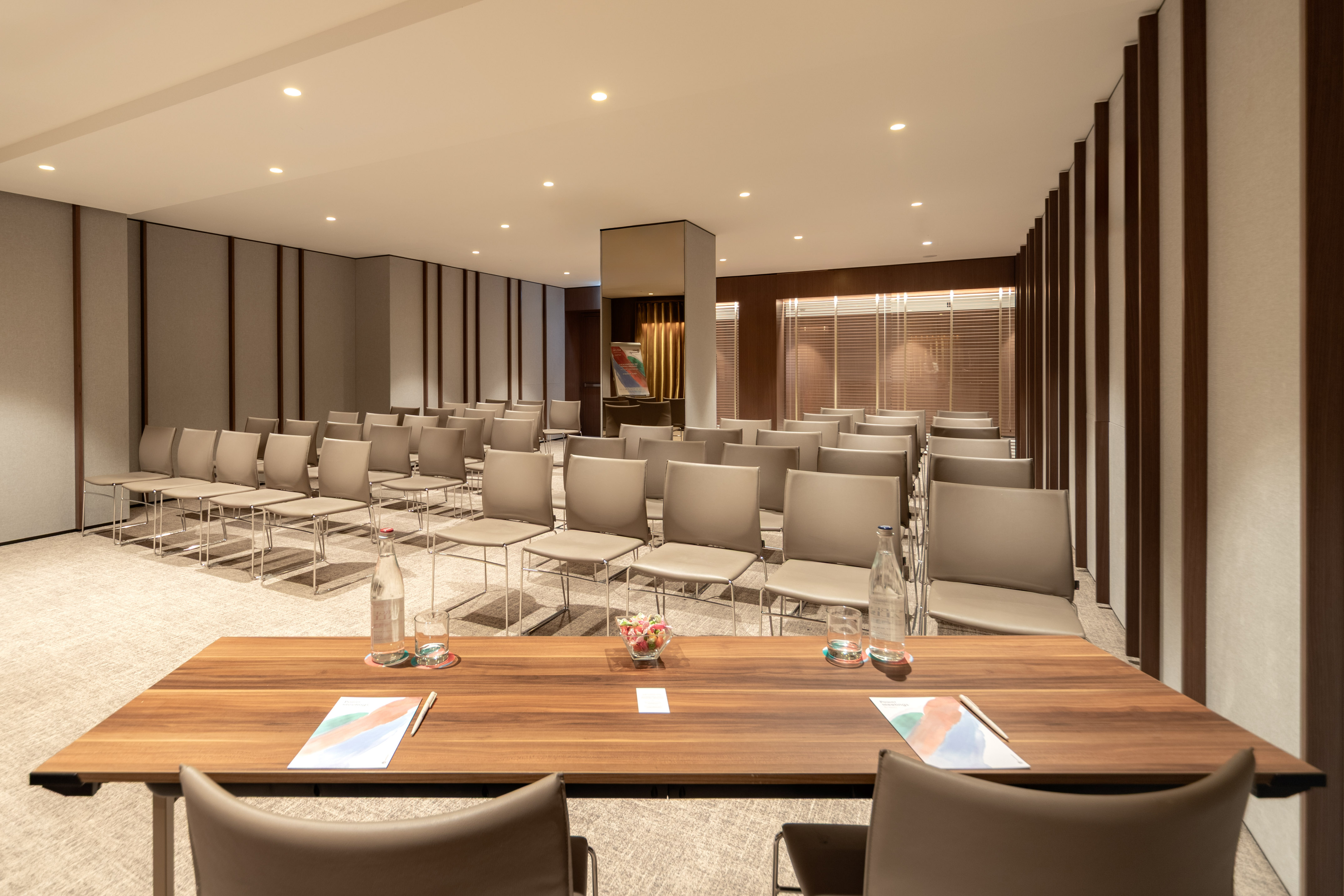 Empty modern conference room with rows of chairs and a wooden foreground table.