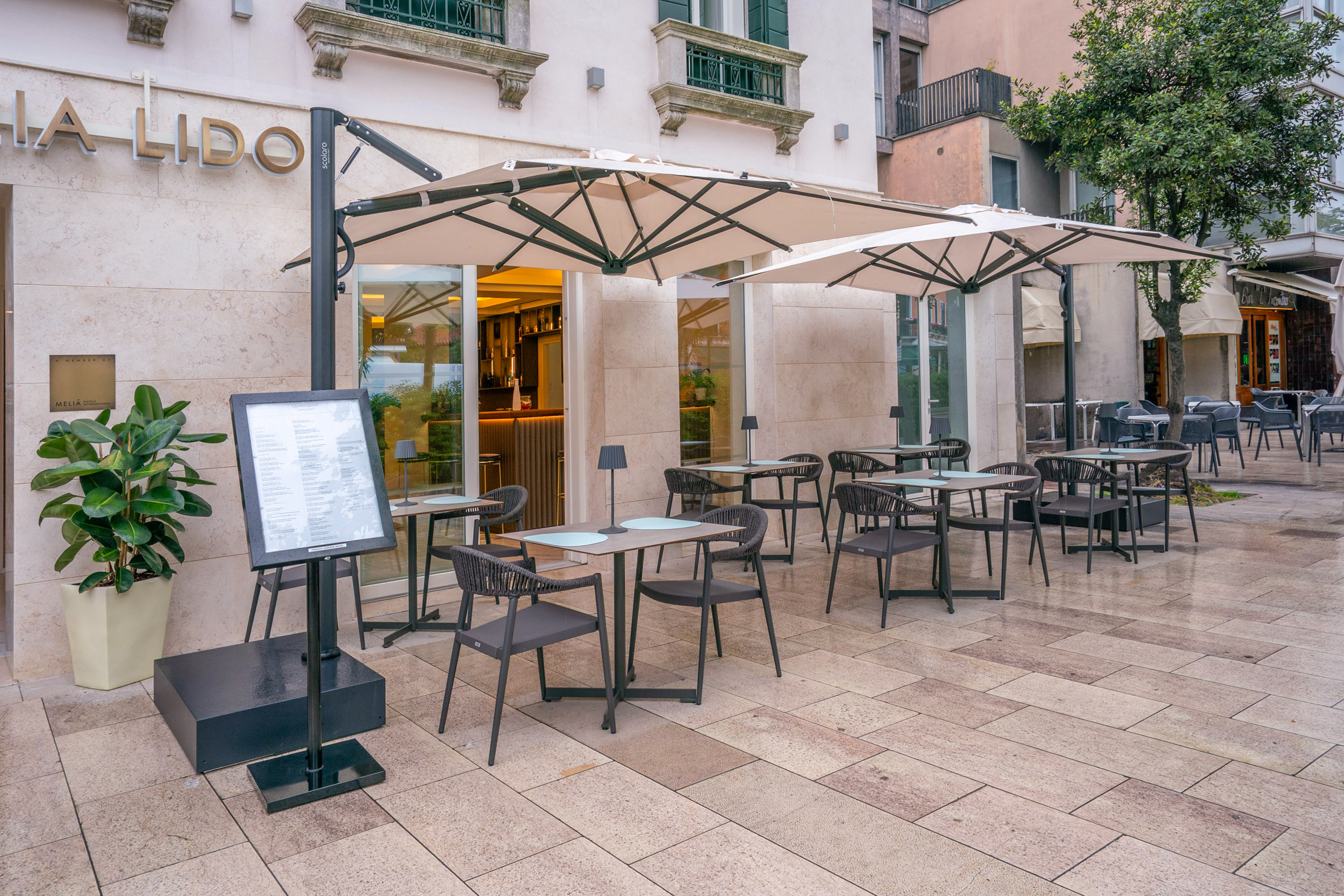 Outdoor cafe terrace at Lido restaurant with tables, chairs, and umbrellas.