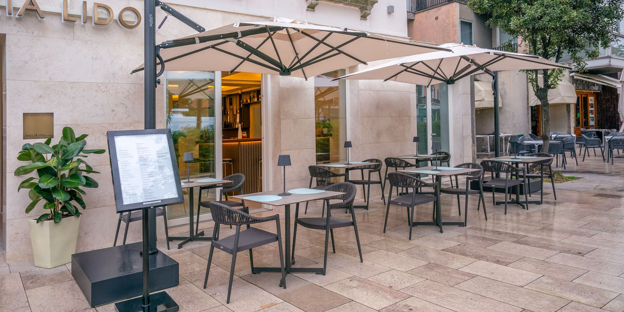 Outdoor cafe terrace at Lido restaurant with tables, chairs, and umbrellas.