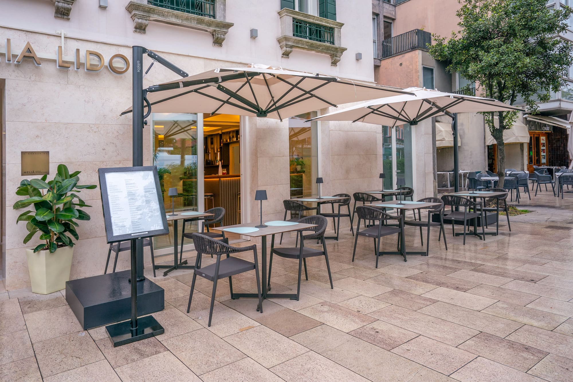 Outdoor cafe terrace at Lido restaurant with tables, chairs, and umbrellas.