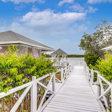 a white wooden walkway with a white railing and a white fence