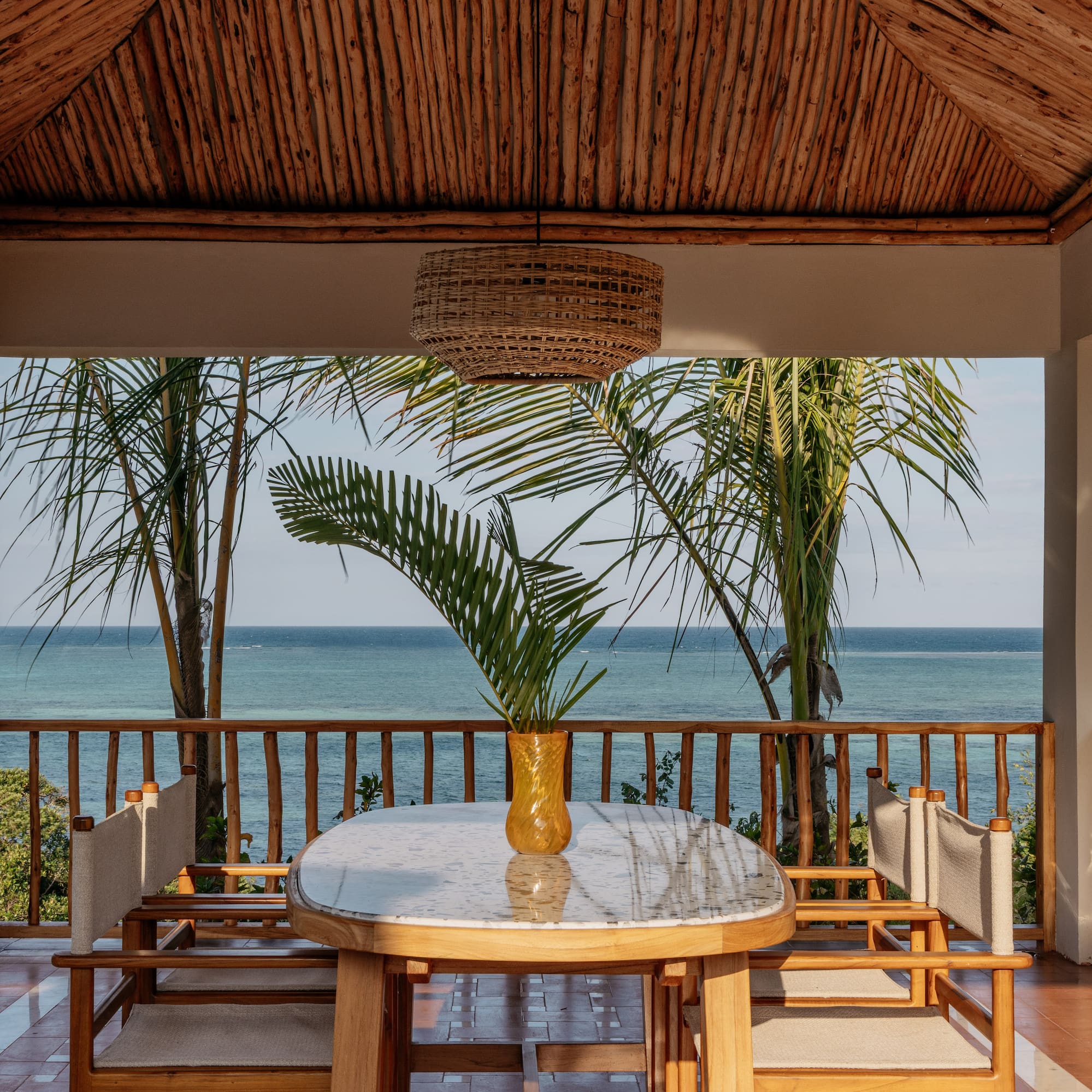 a table with chairs and a vase of palm trees on the deck