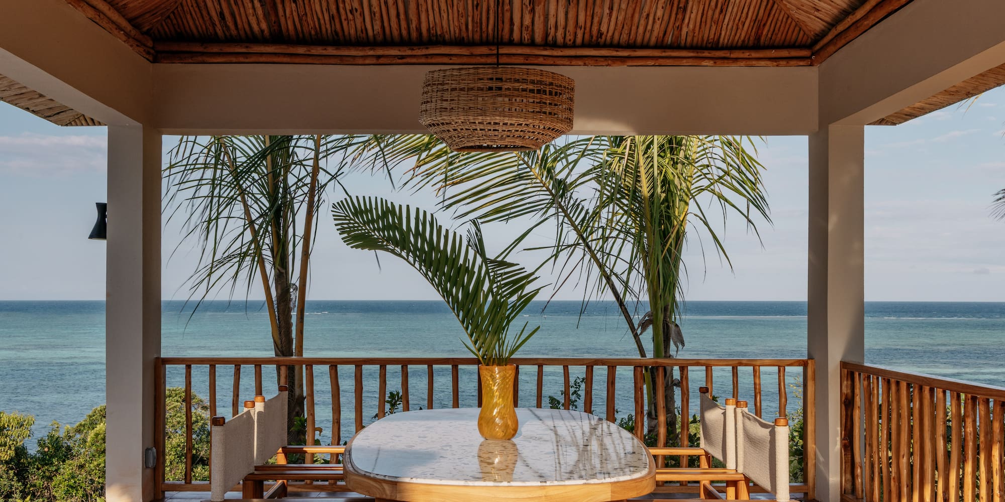 a table with chairs and a vase of palm trees on the deck