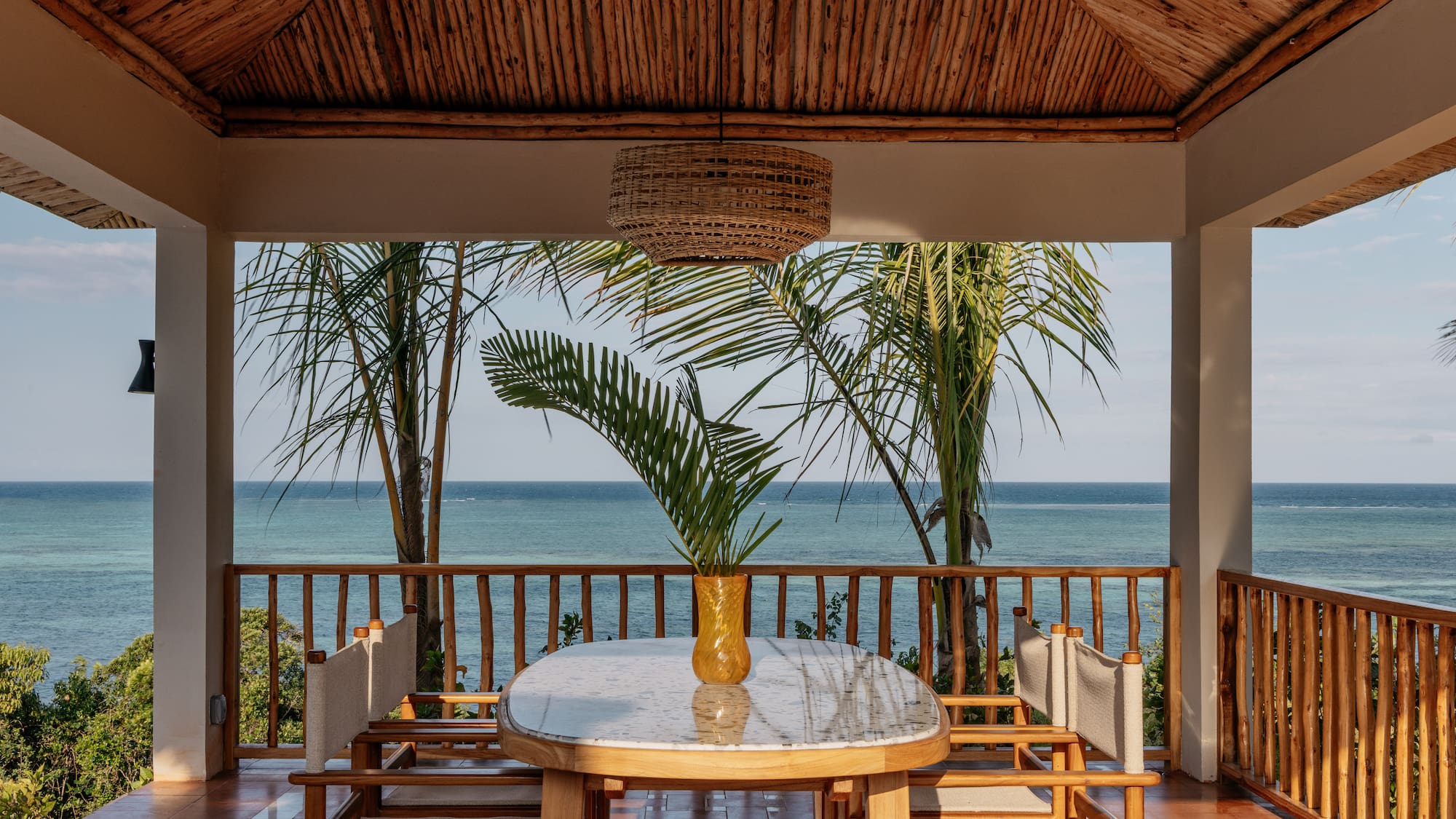 a table with chairs and a vase of palm trees on the deck
